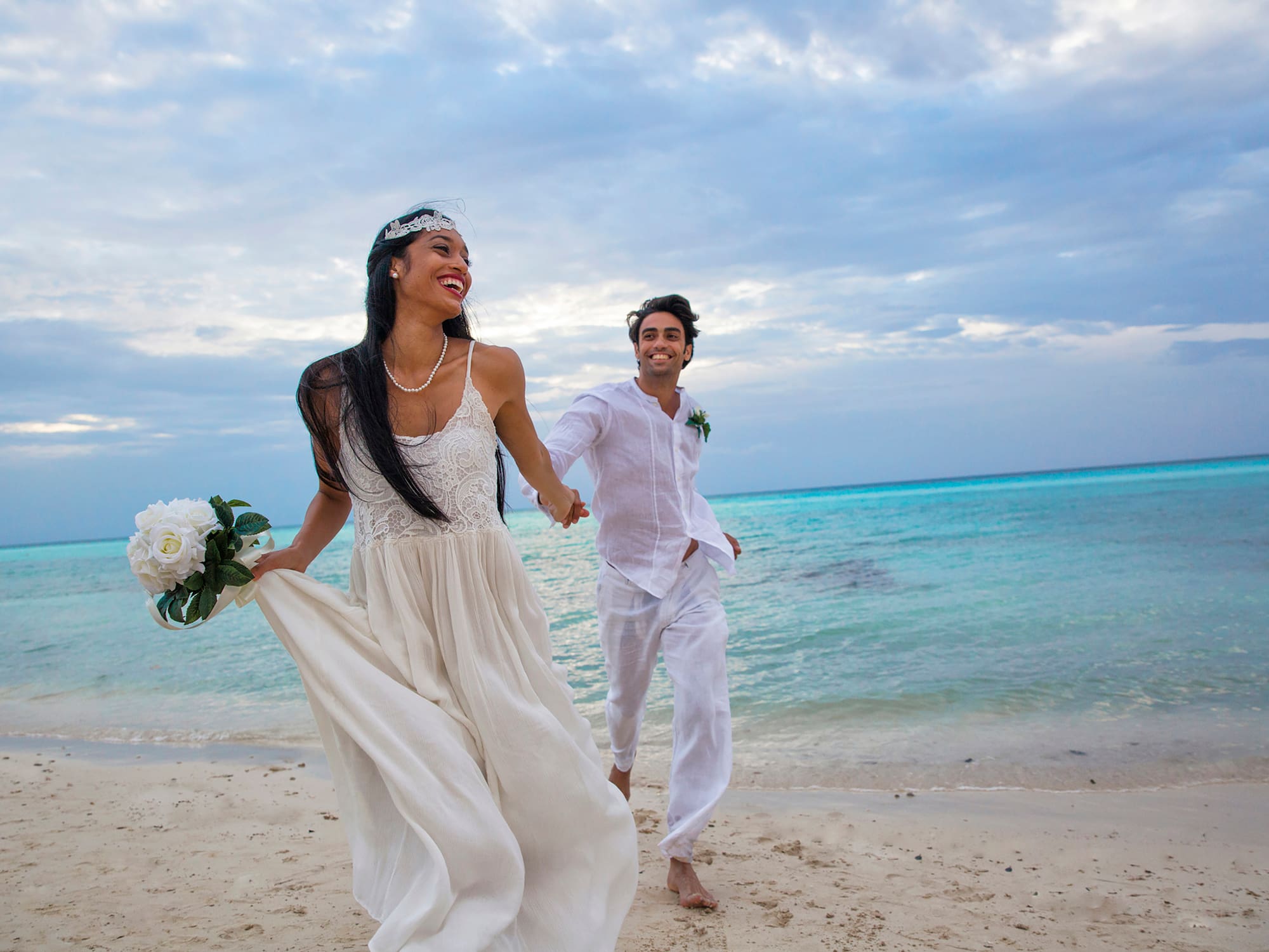 a man and woman holding hands and running on a beach