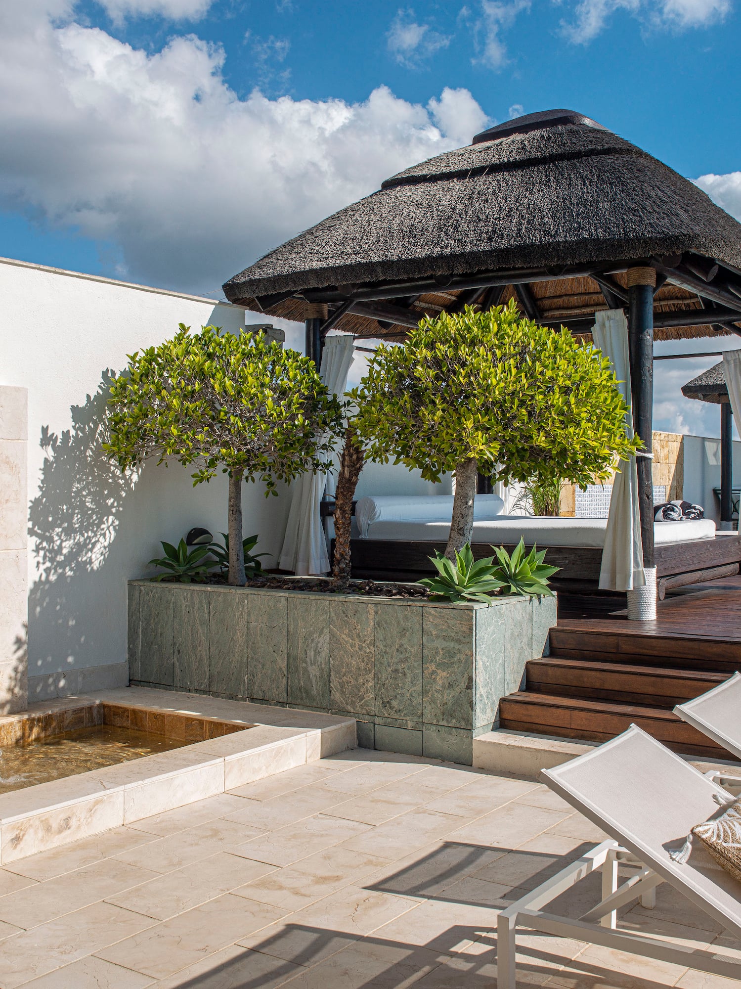 a patio with a thatched roof and a fountain