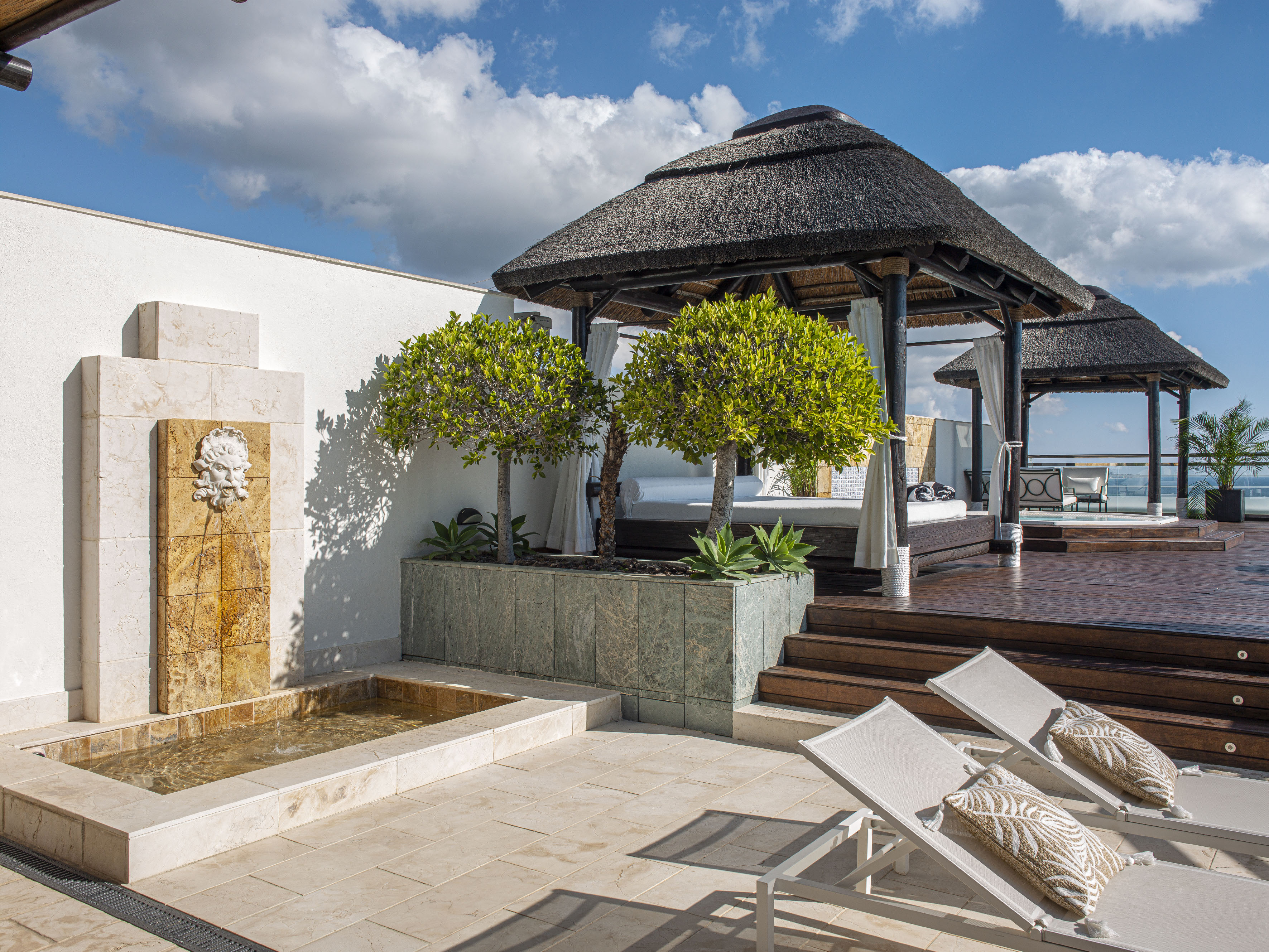 a patio with a thatched roof and a fountain
