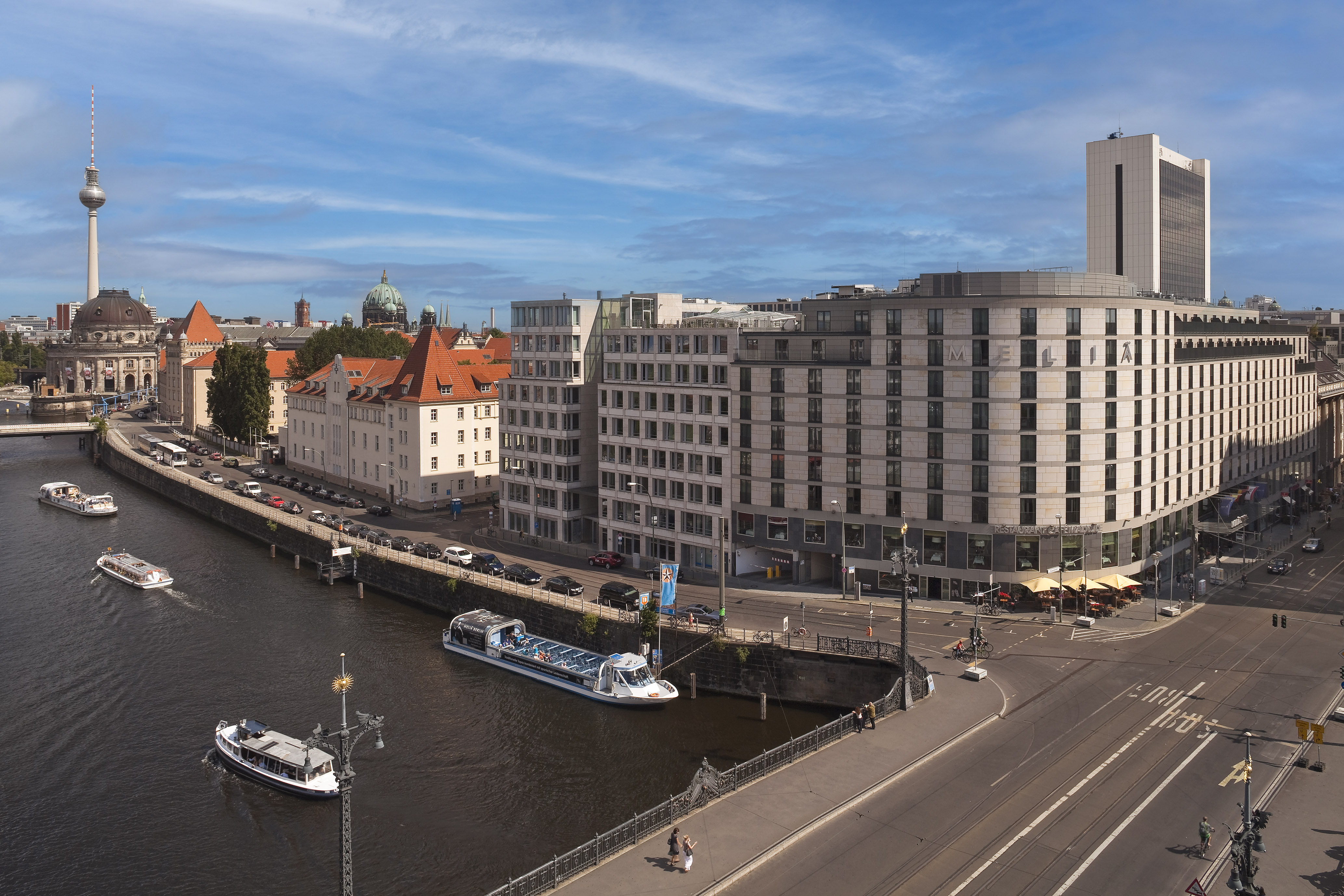 Berlin Spree River cityscape with boats, TV Tower, and diverse architecture.