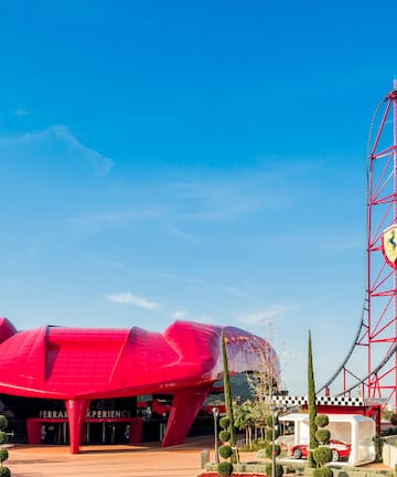 a red roller coaster with a red structure in the background