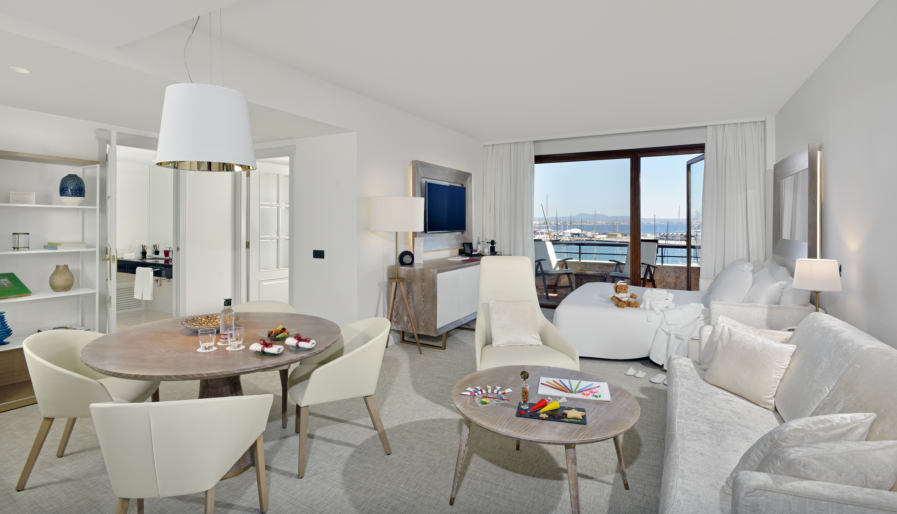 Luxury hotel suite with marina view, dining area, and children's crafts.