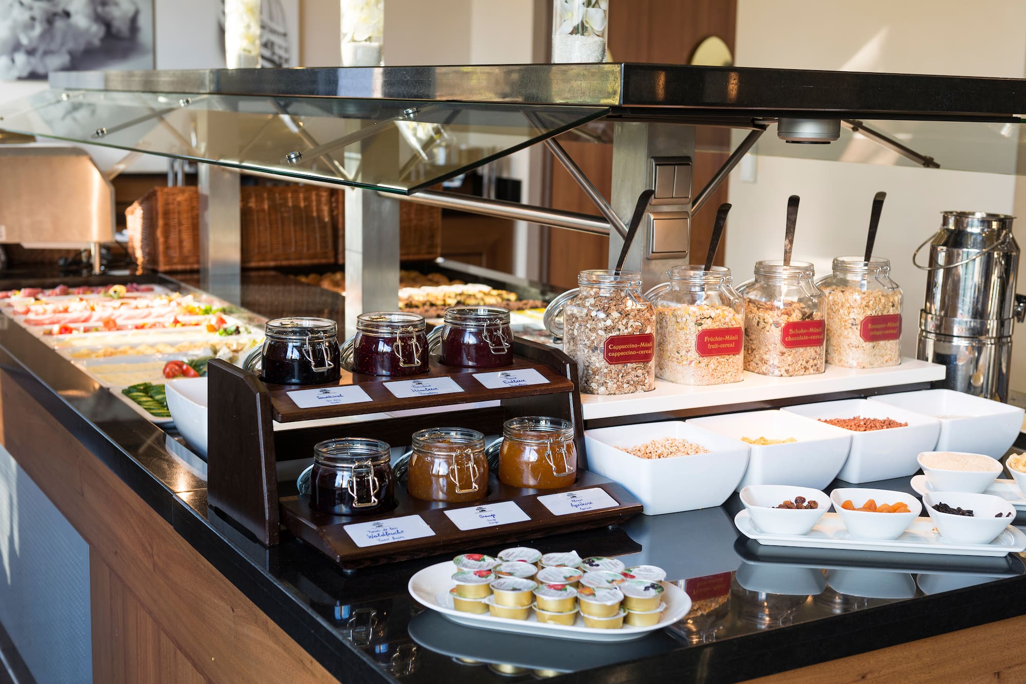 Breakfast buffet with assorted fruit jams, cereals, muesli, and dried fruit.
