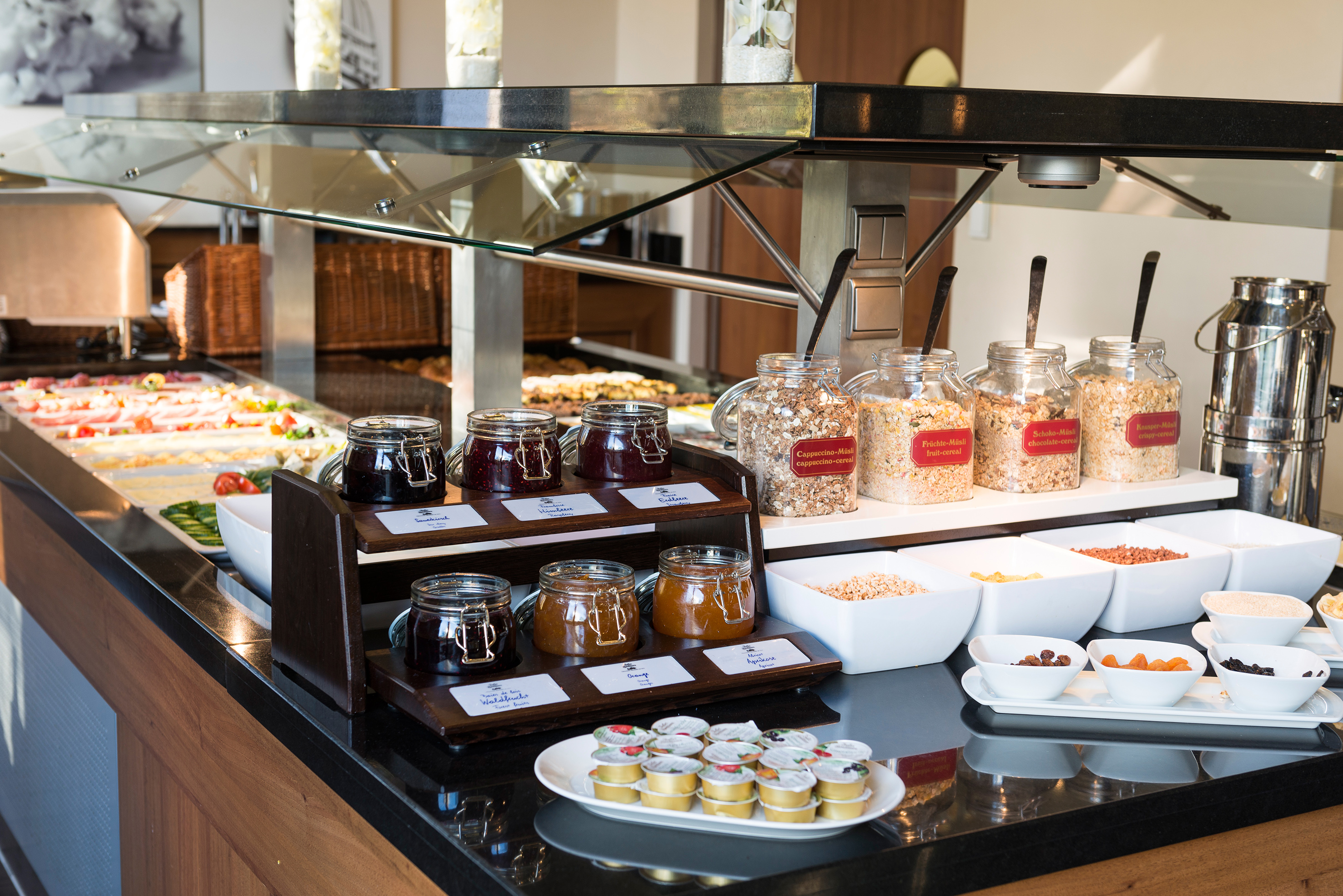 Breakfast buffet with assorted fruit jams, cereals, muesli, and dried fruit.
