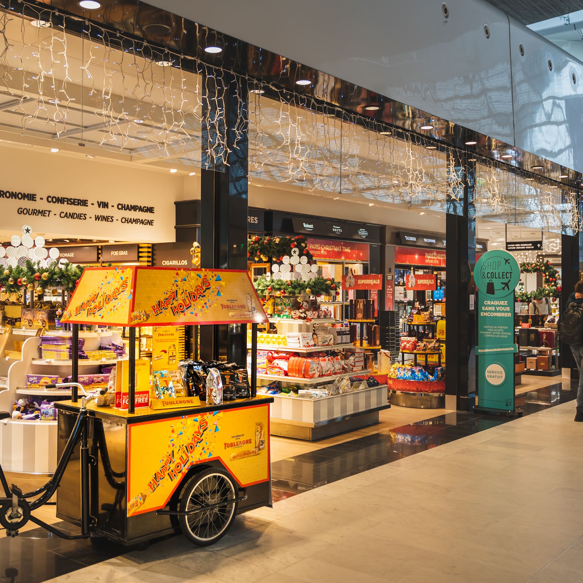 A man strolls by a food cart in a mall.