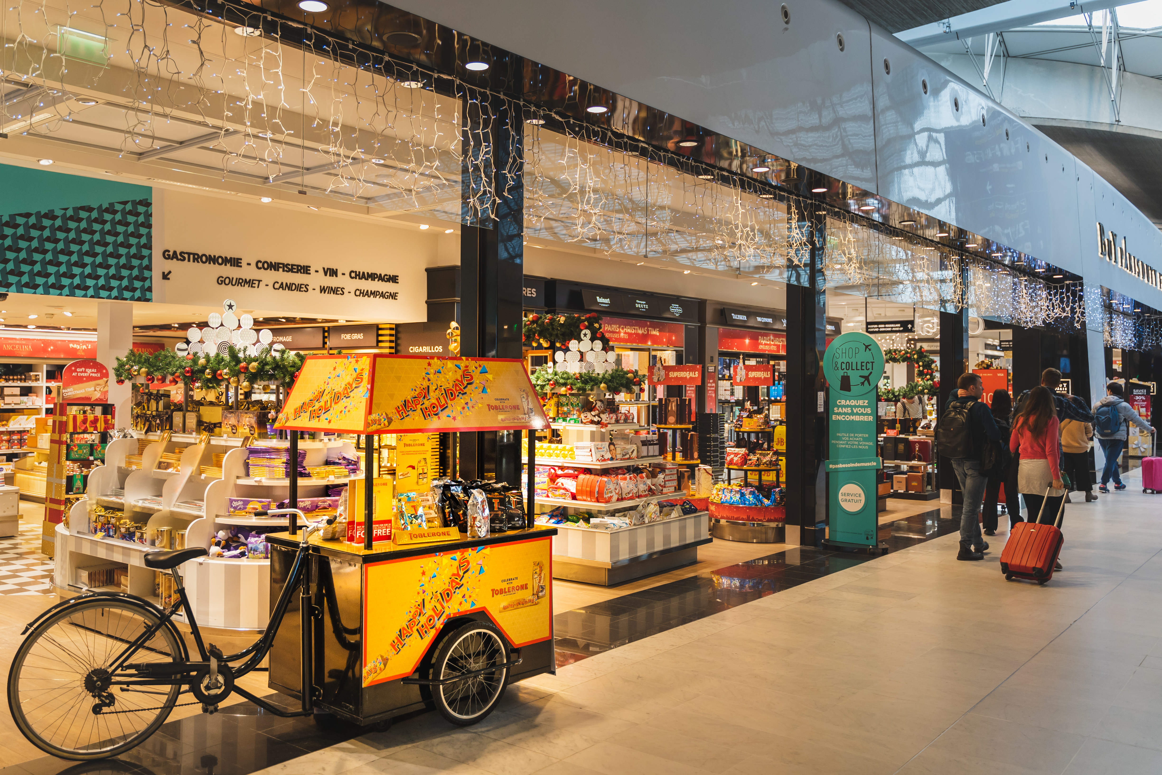 A man strolls by a food cart in a mall.