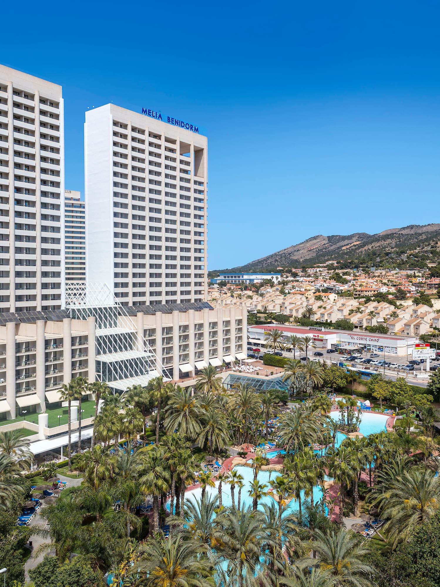 a large white building with palm trees and a pool