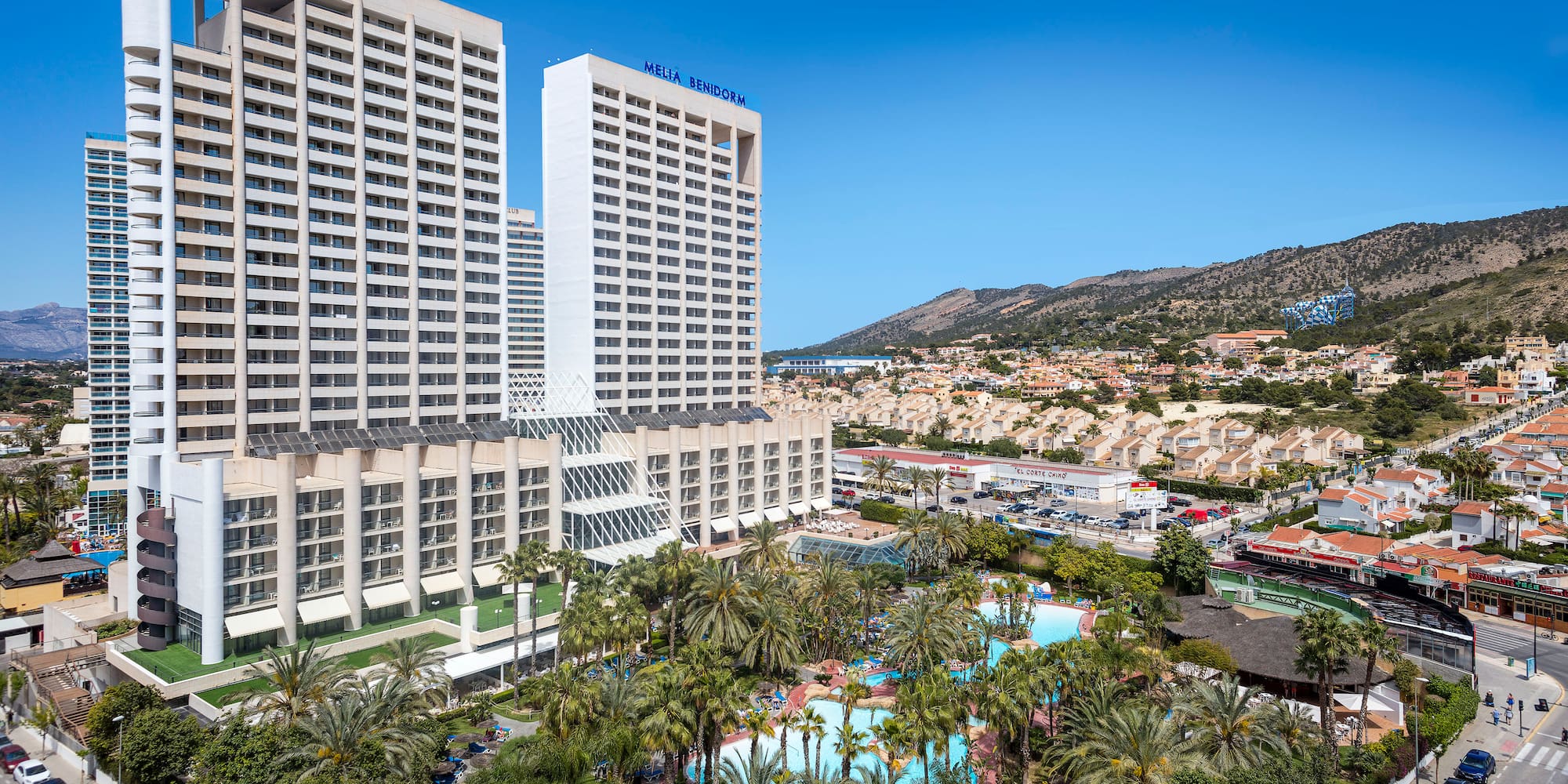 a large white building with palm trees and a pool