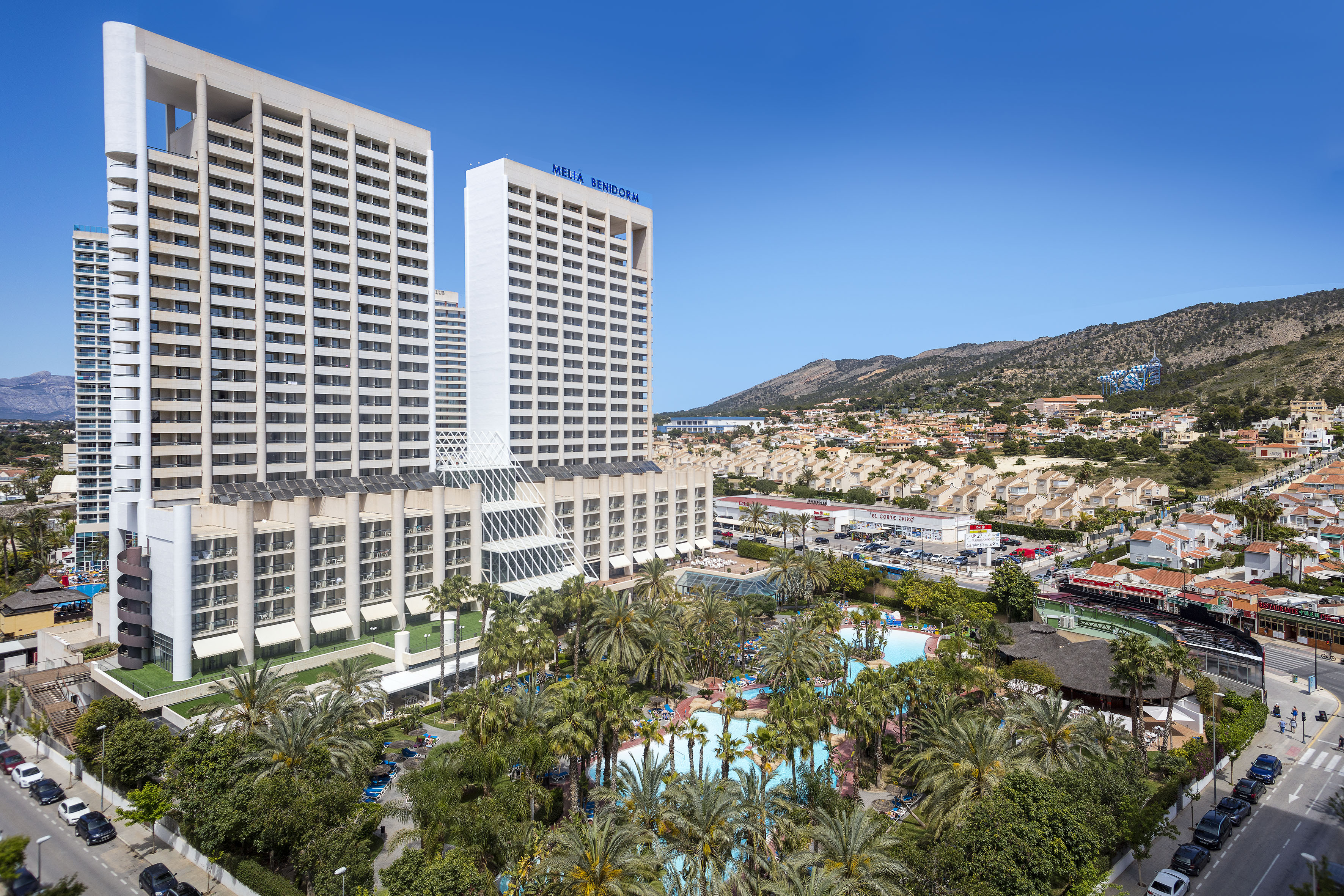 a large white building with palm trees and a pool