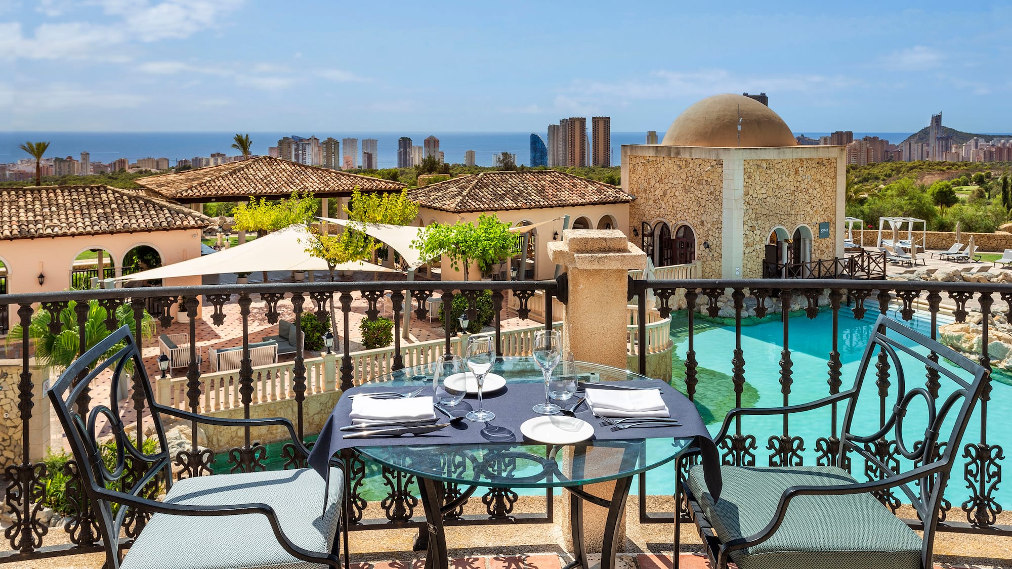 a table and chairs on a balcony overlooking a city
