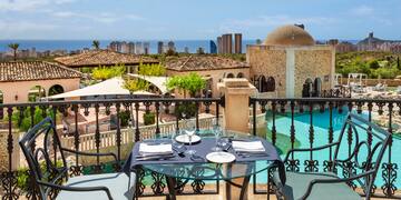 a table and chairs on a balcony overlooking a city