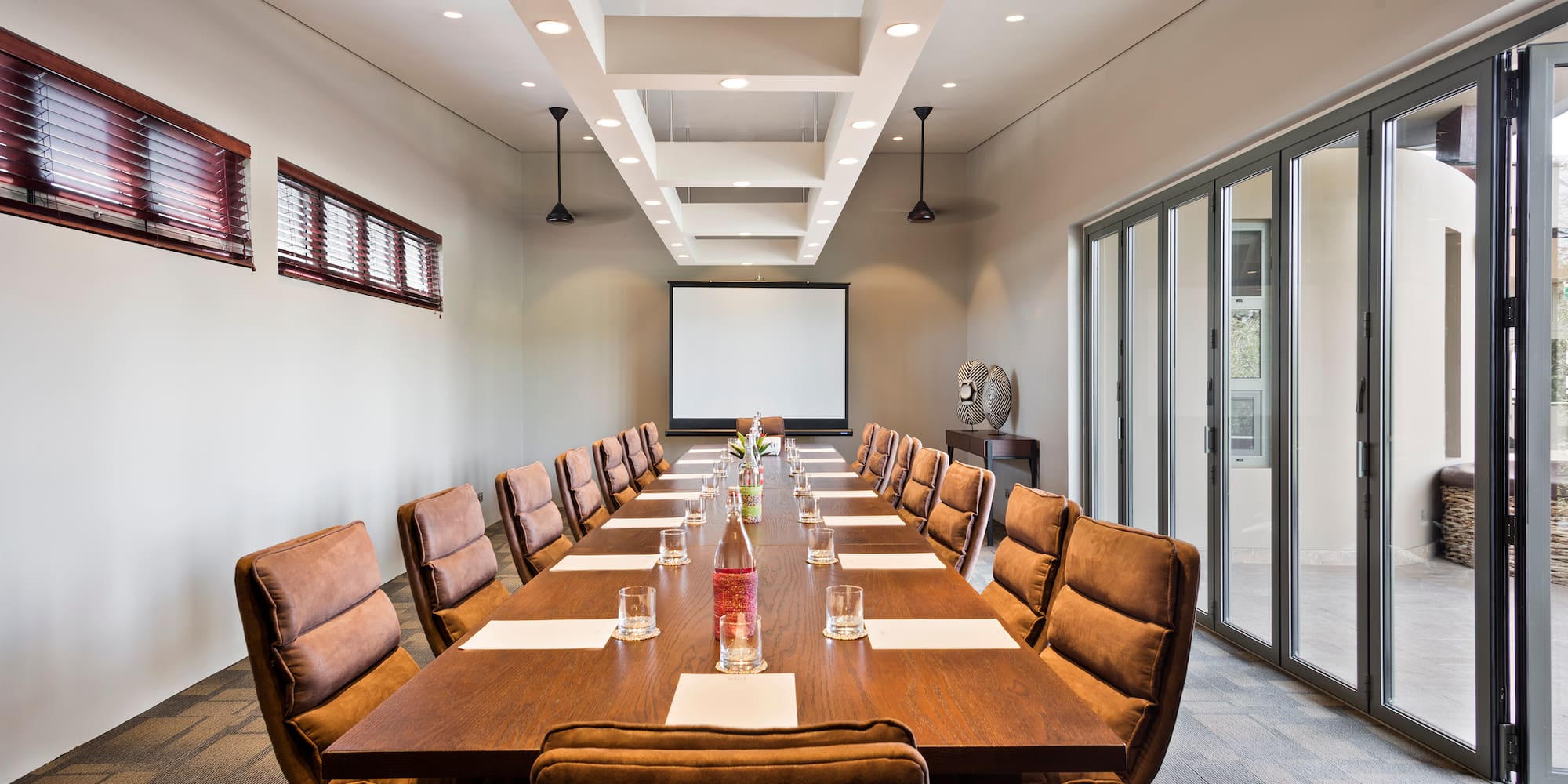 a long conference table with chairs and a projector screen
