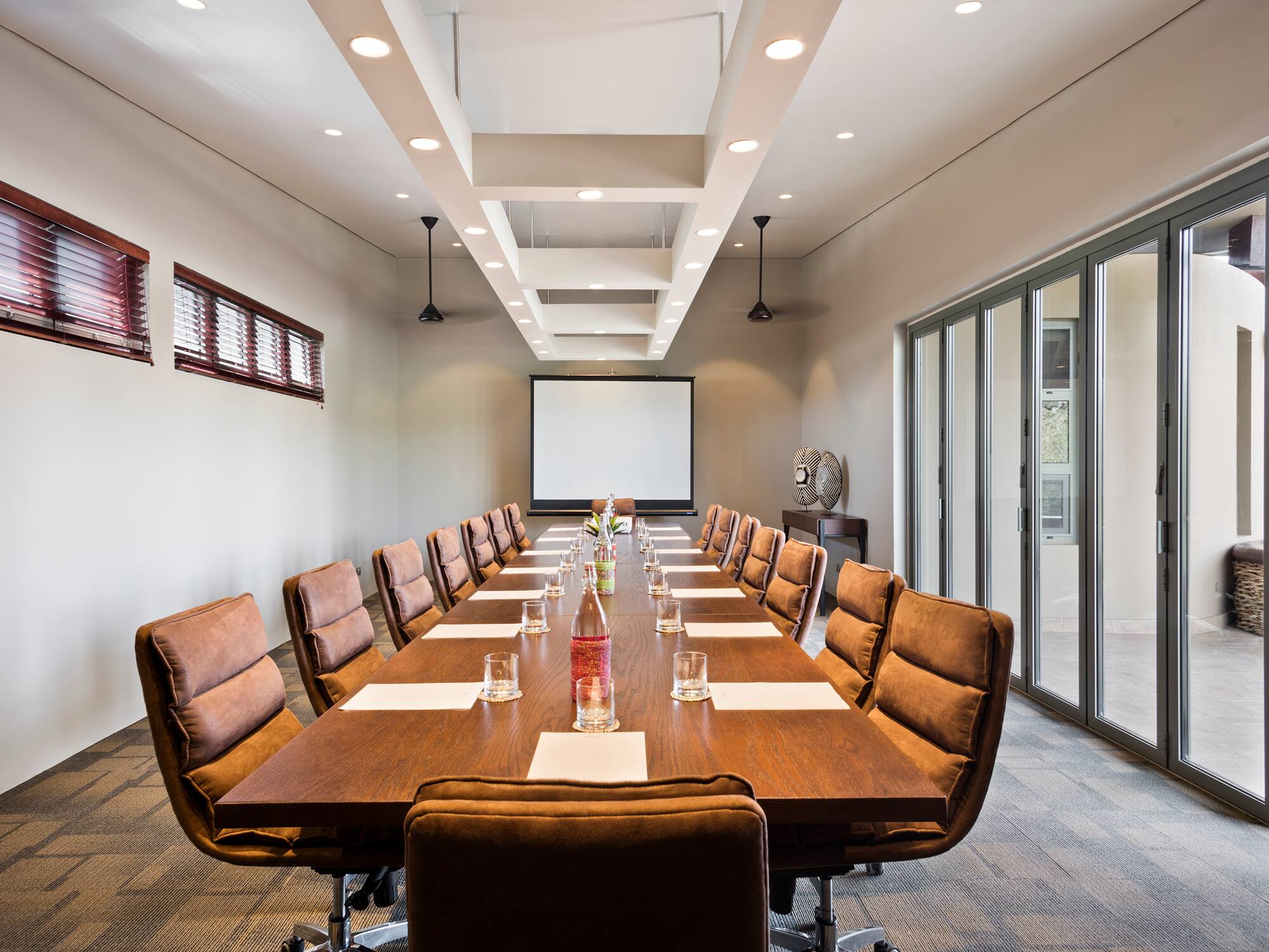 a long conference table with chairs and a projector screen