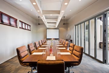 a long conference table with chairs and a projector screen