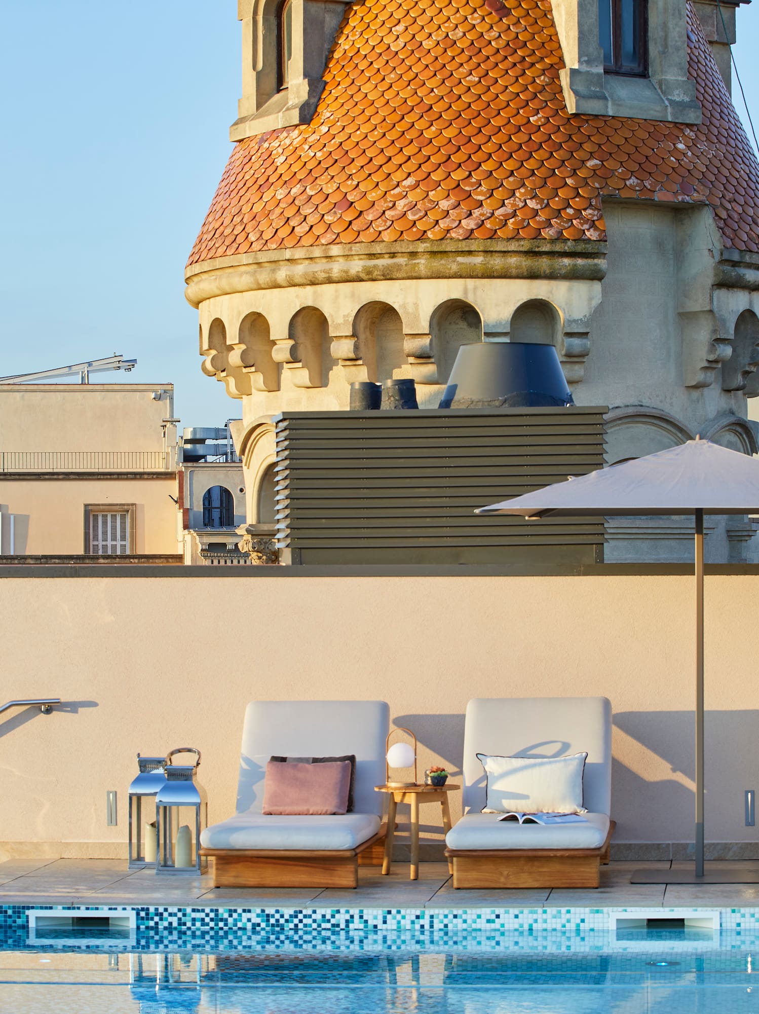 a pool with chairs and umbrellas by a building