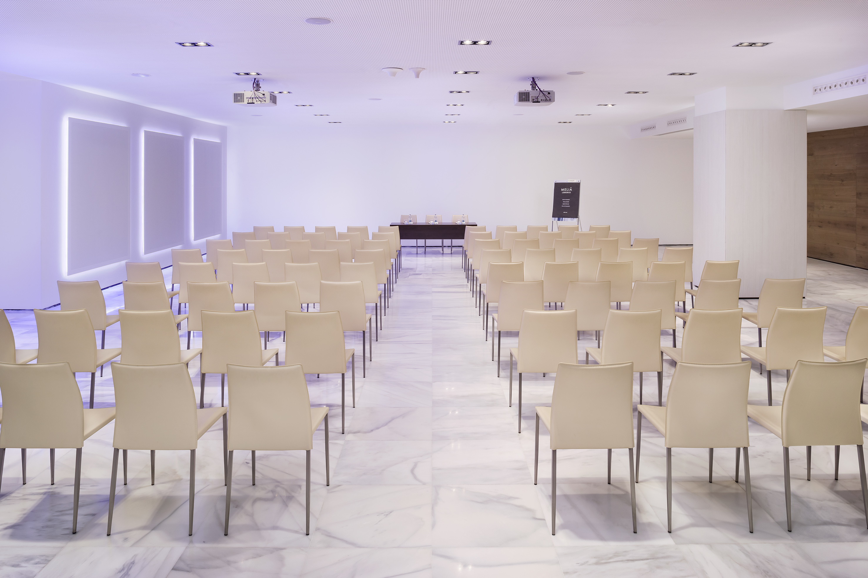 Empty modern conference room with cream chairs, projector, and front table.