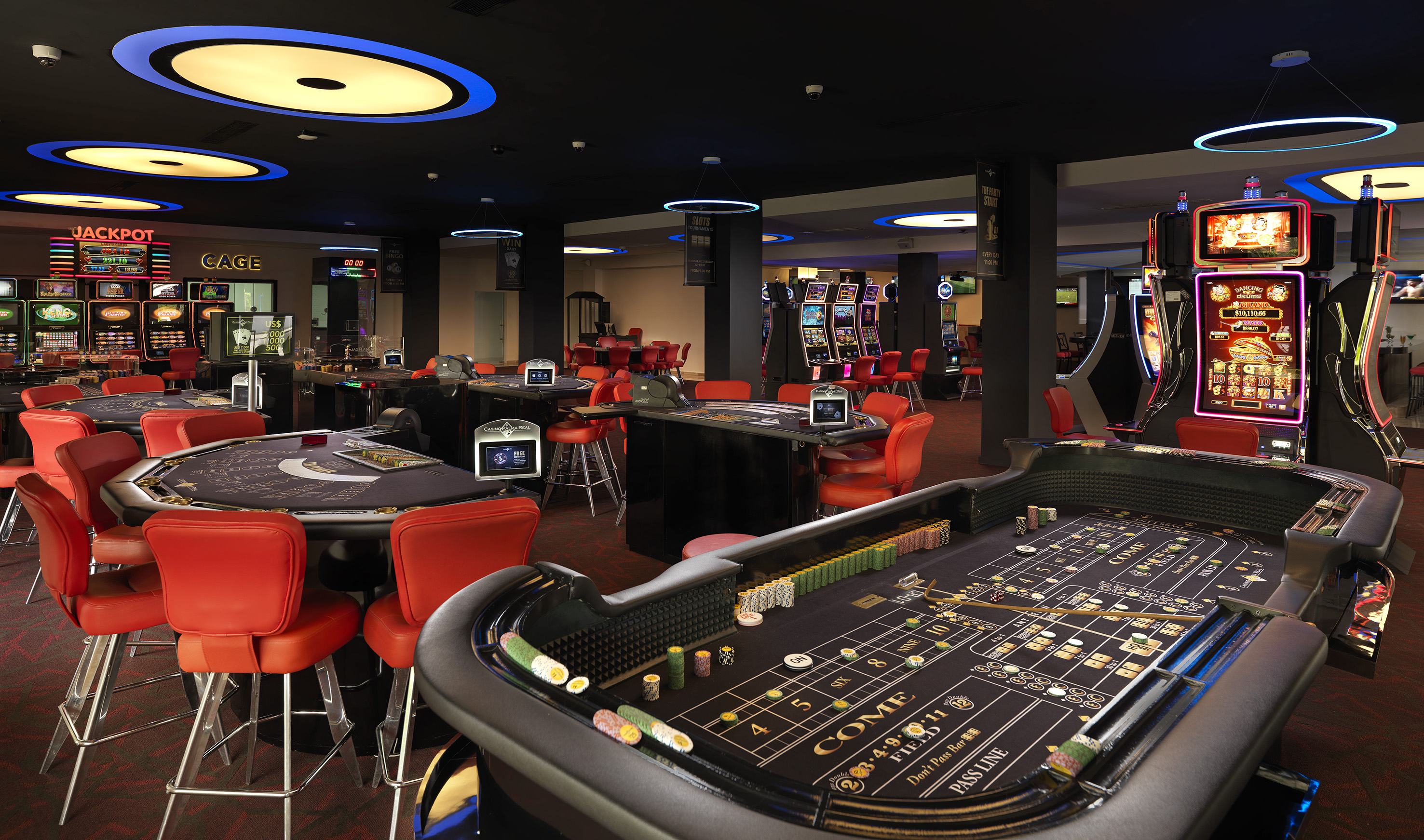 Modern casino featuring a prominent craps table, slot machines, and card games.