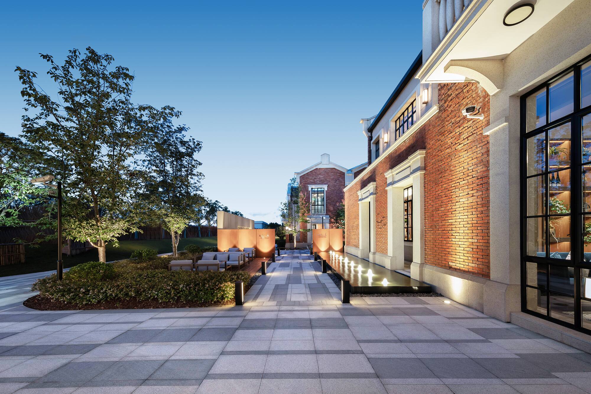 Modern brick courtyard, outdoor seating, water feature, and evening lighting.