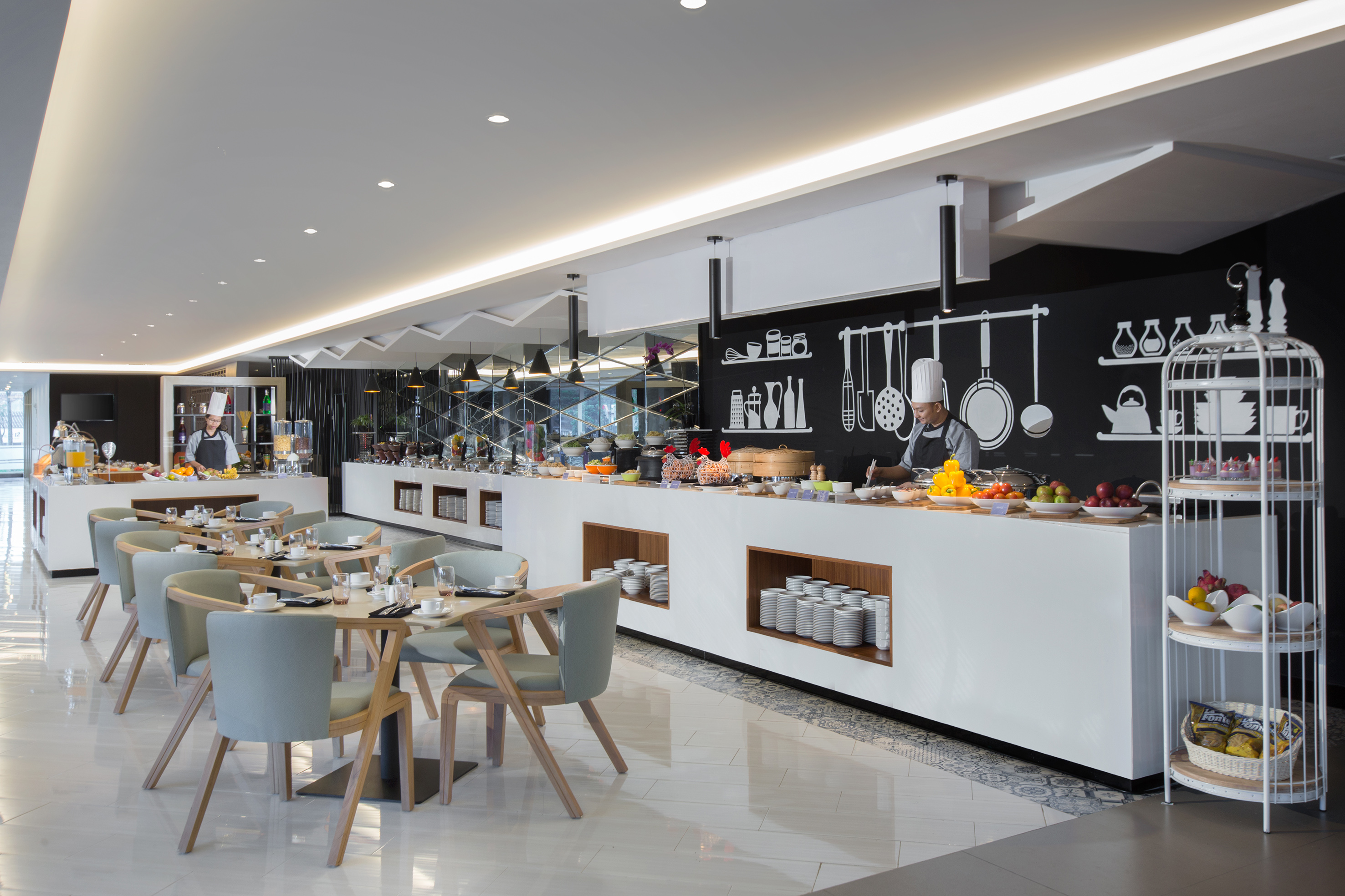 Modern hotel breakfast buffet with chef, fresh food, and bright dining area.