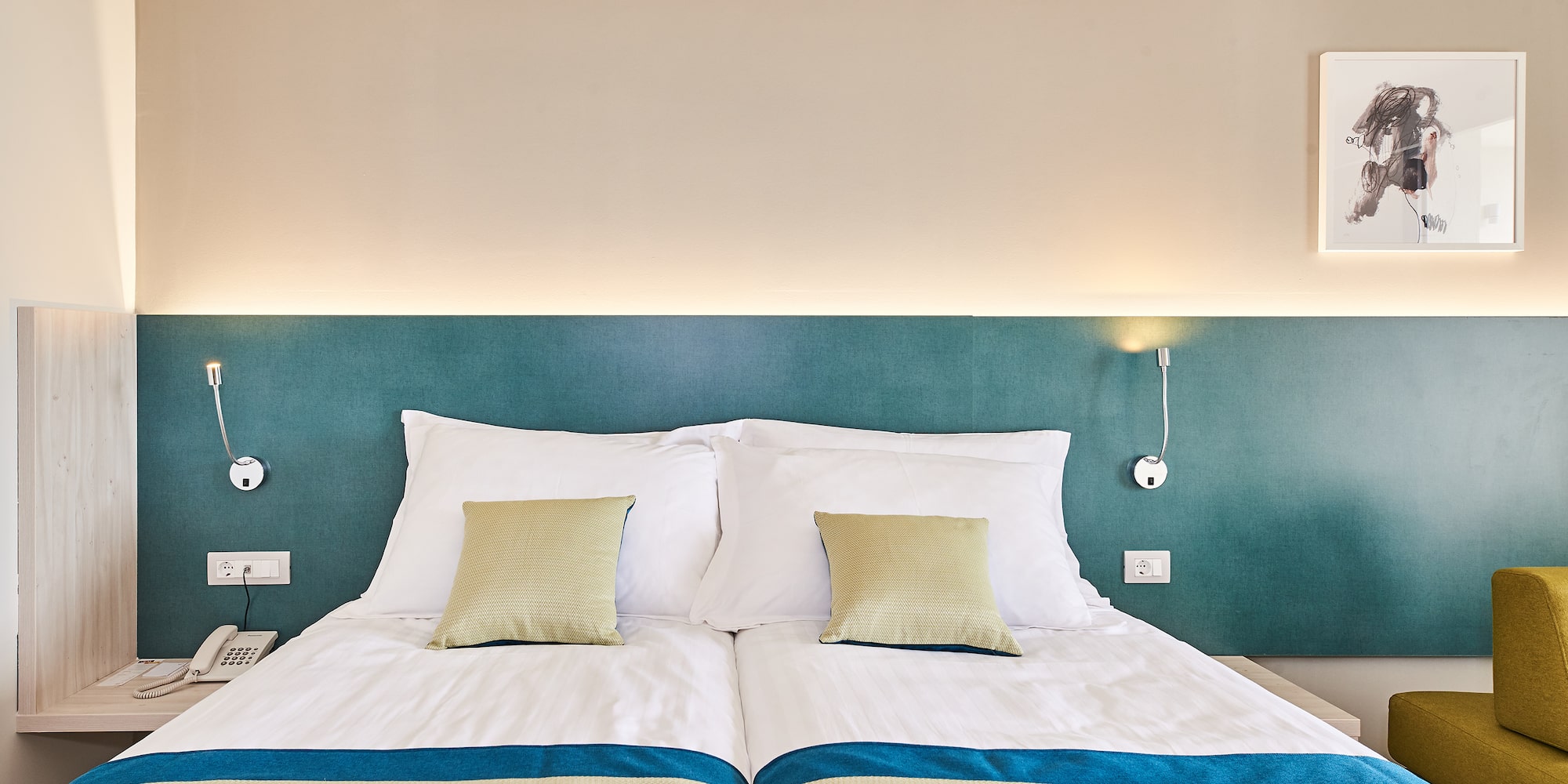 a bed with pillows and a lamp on the wall