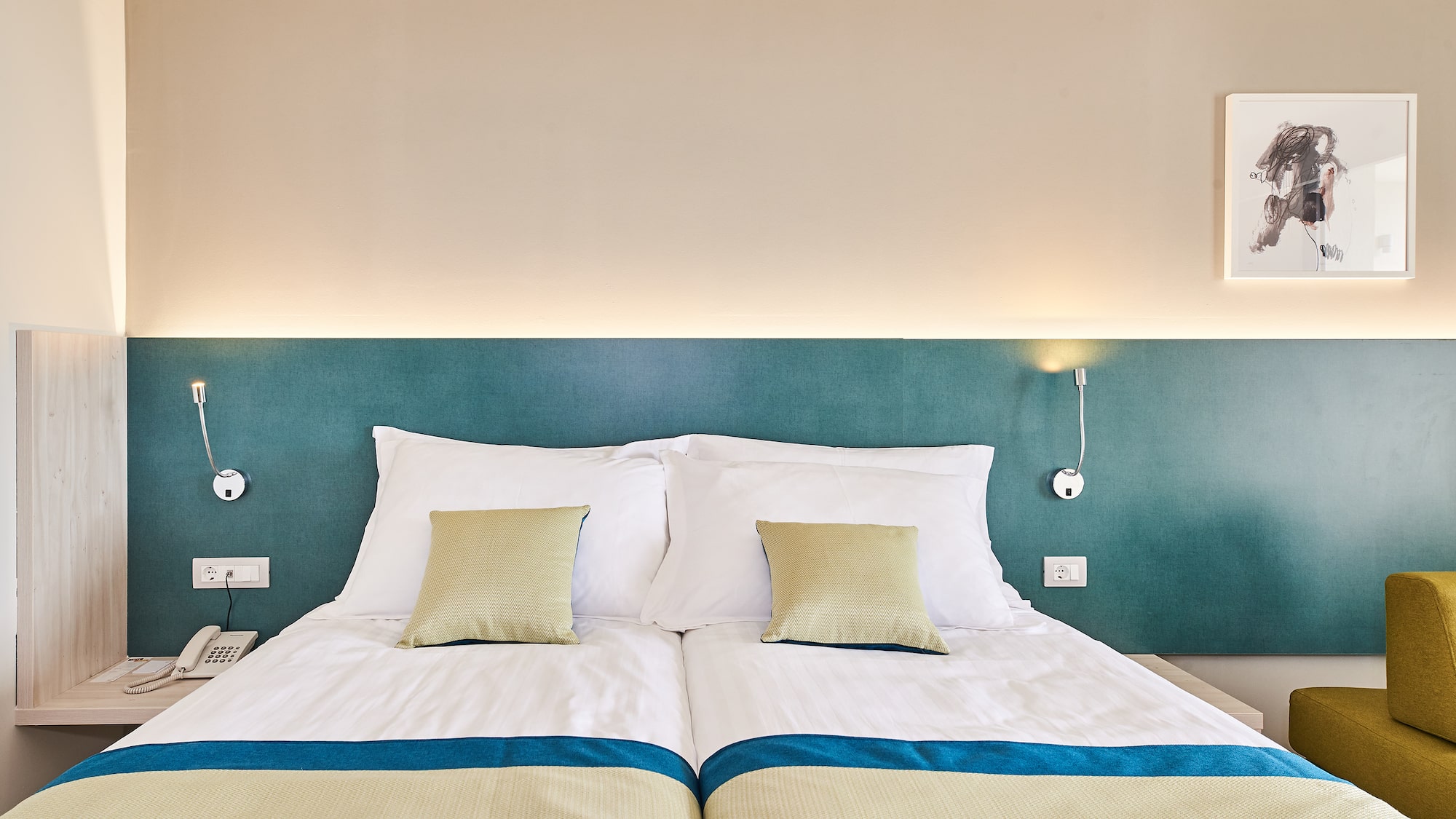 a bed with pillows and a lamp on the wall