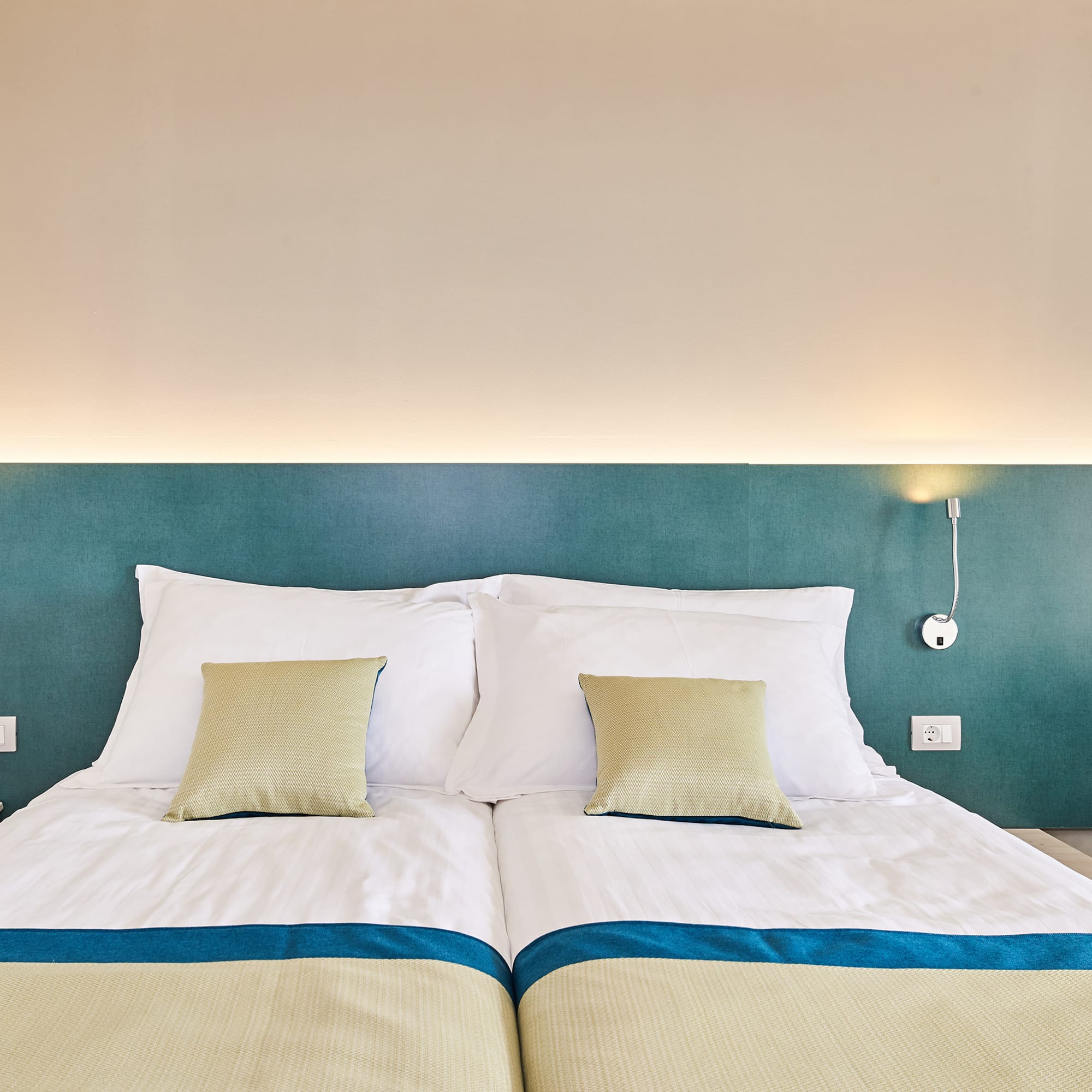 a bed with pillows and a lamp on the wall