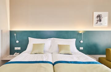 a bed with pillows and a lamp on the wall