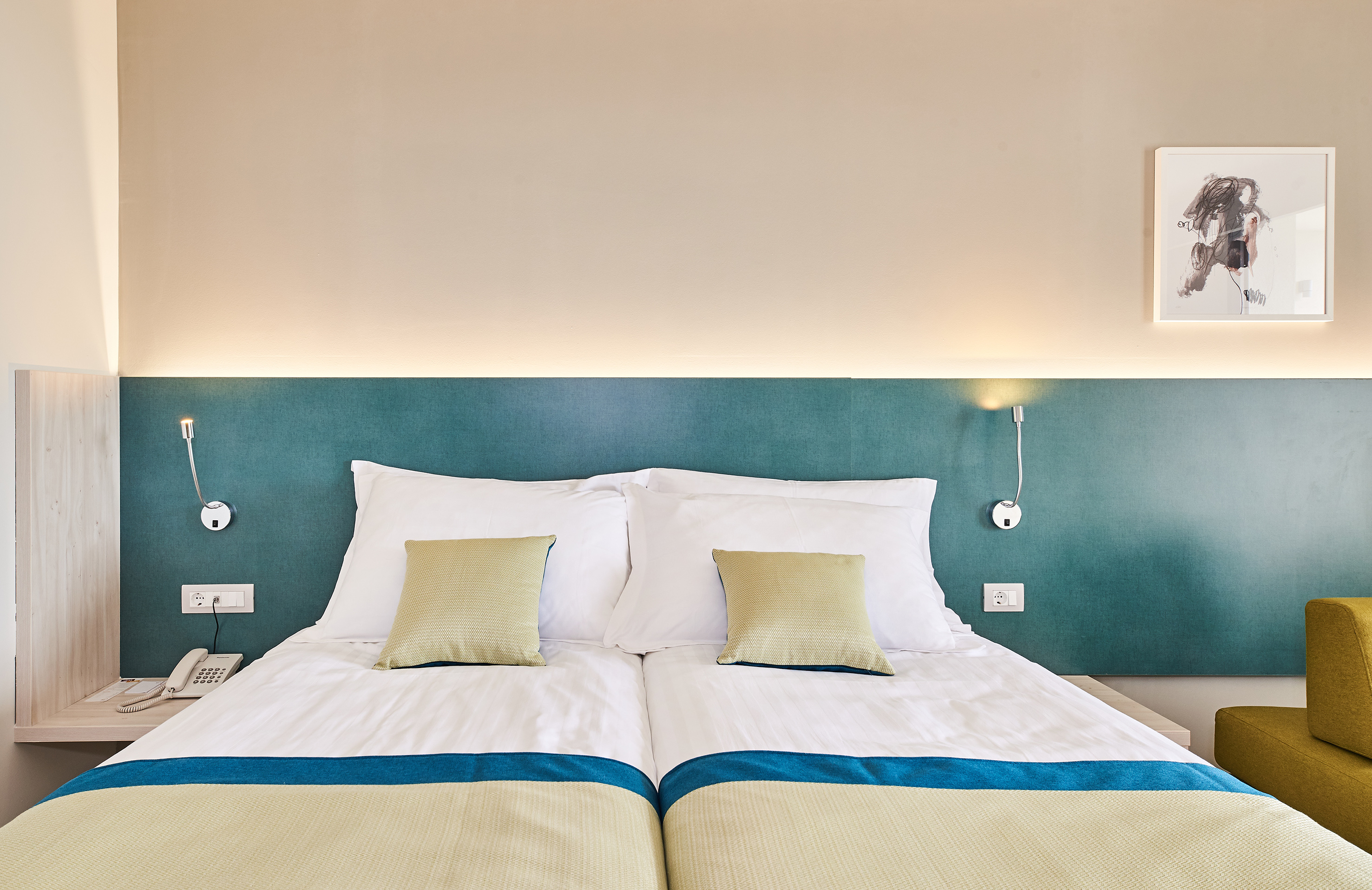 a bed with pillows and a lamp on the wall