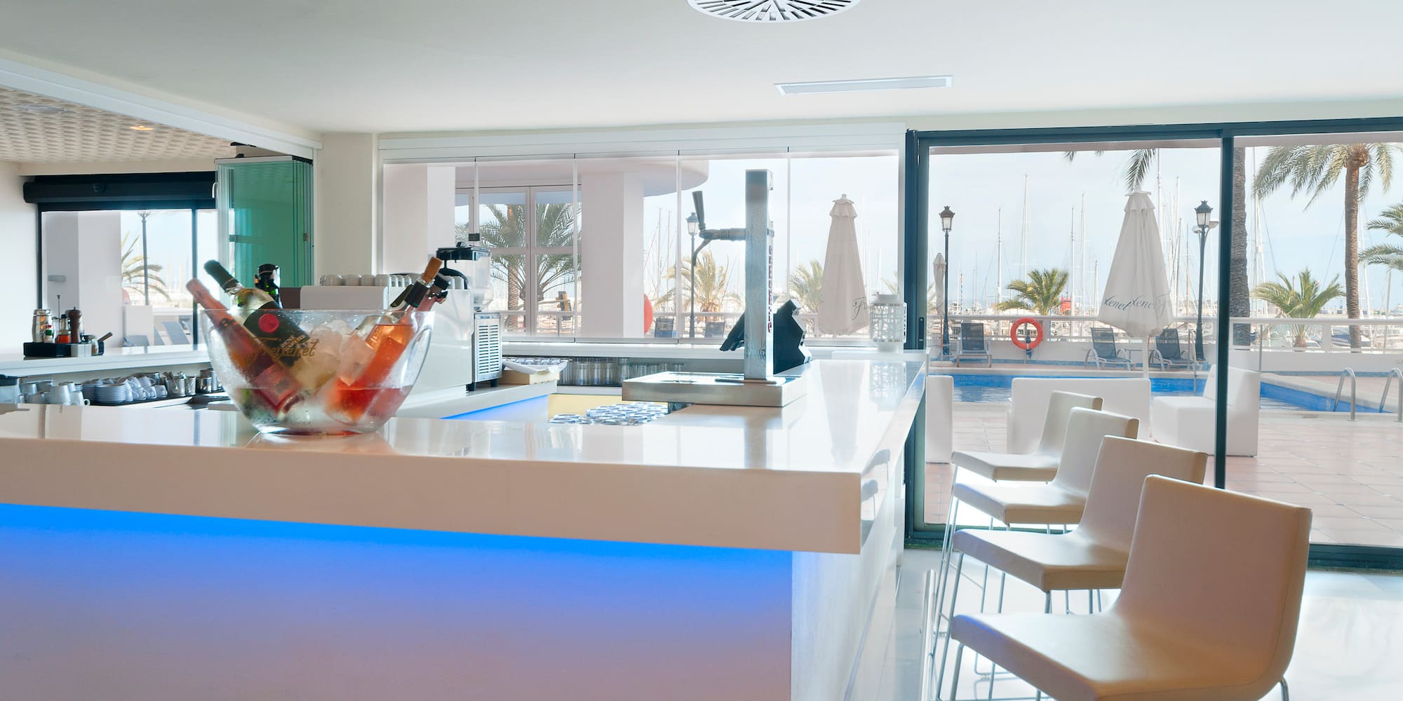 a white bar with chairs and a bowl of ice on it