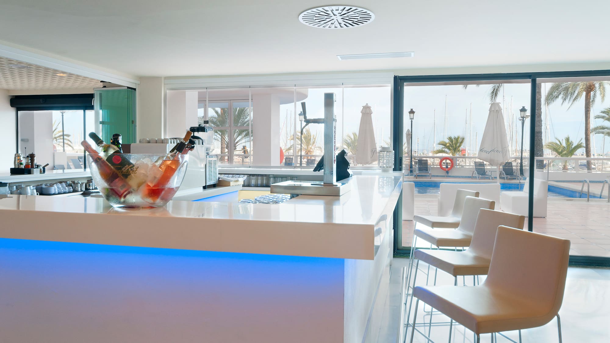 a white bar with chairs and a bowl of ice on it