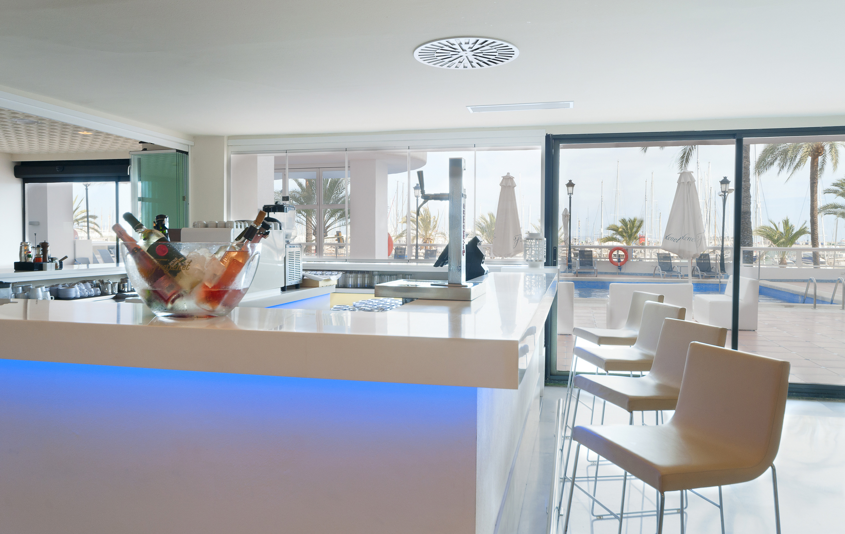 Modern resort bar with blue-lit counter, wine, and marina view.