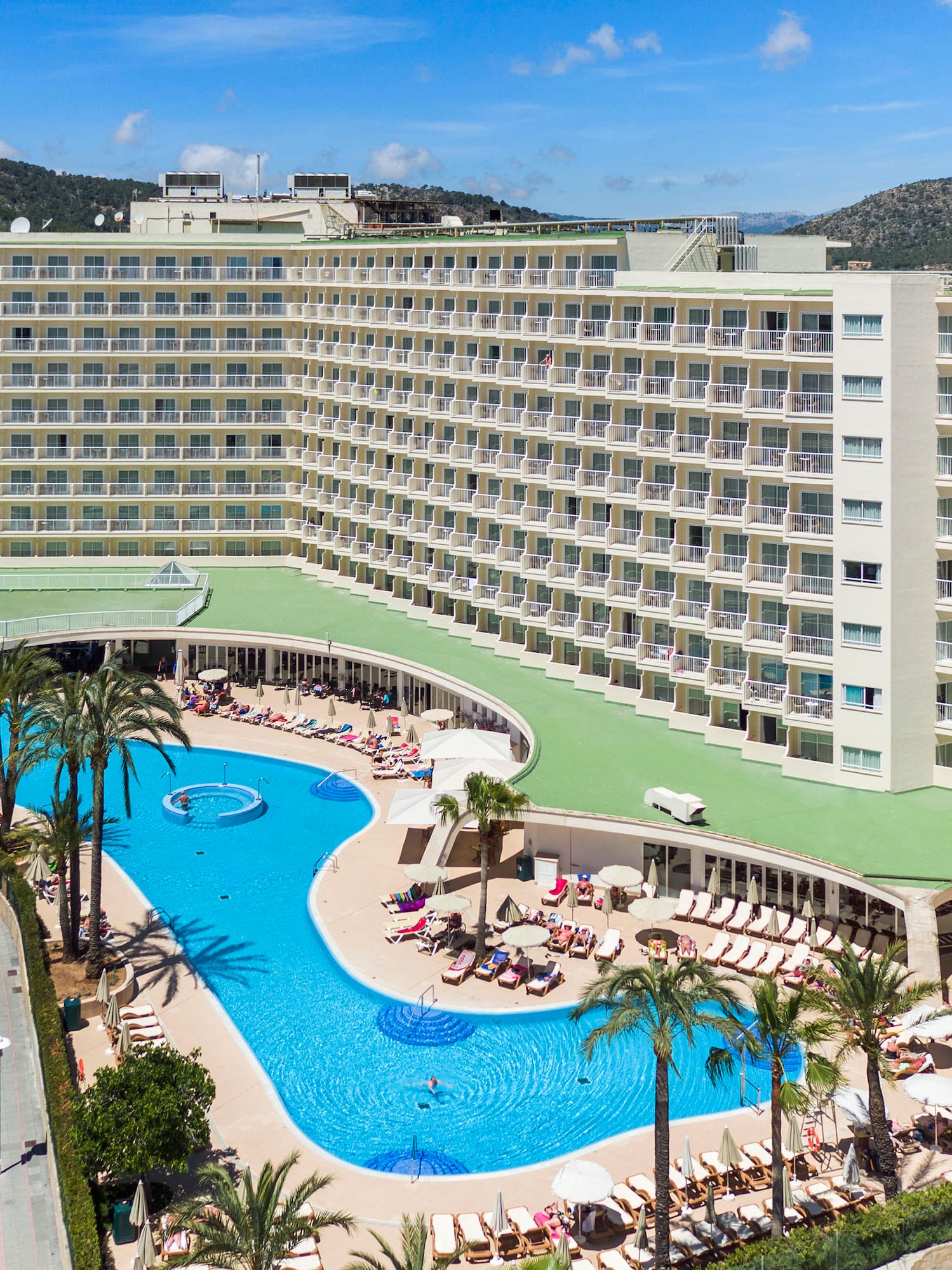 a large hotel with a pool and palm trees