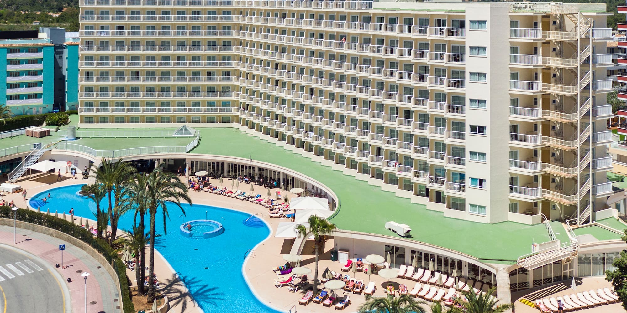 a large hotel with a pool and palm trees