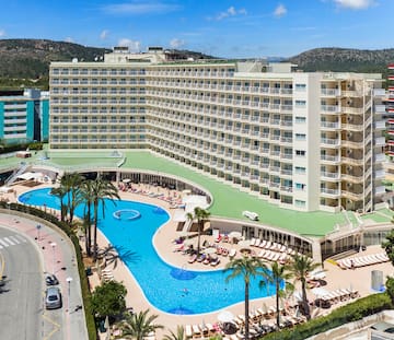 a large hotel with a pool and palm trees