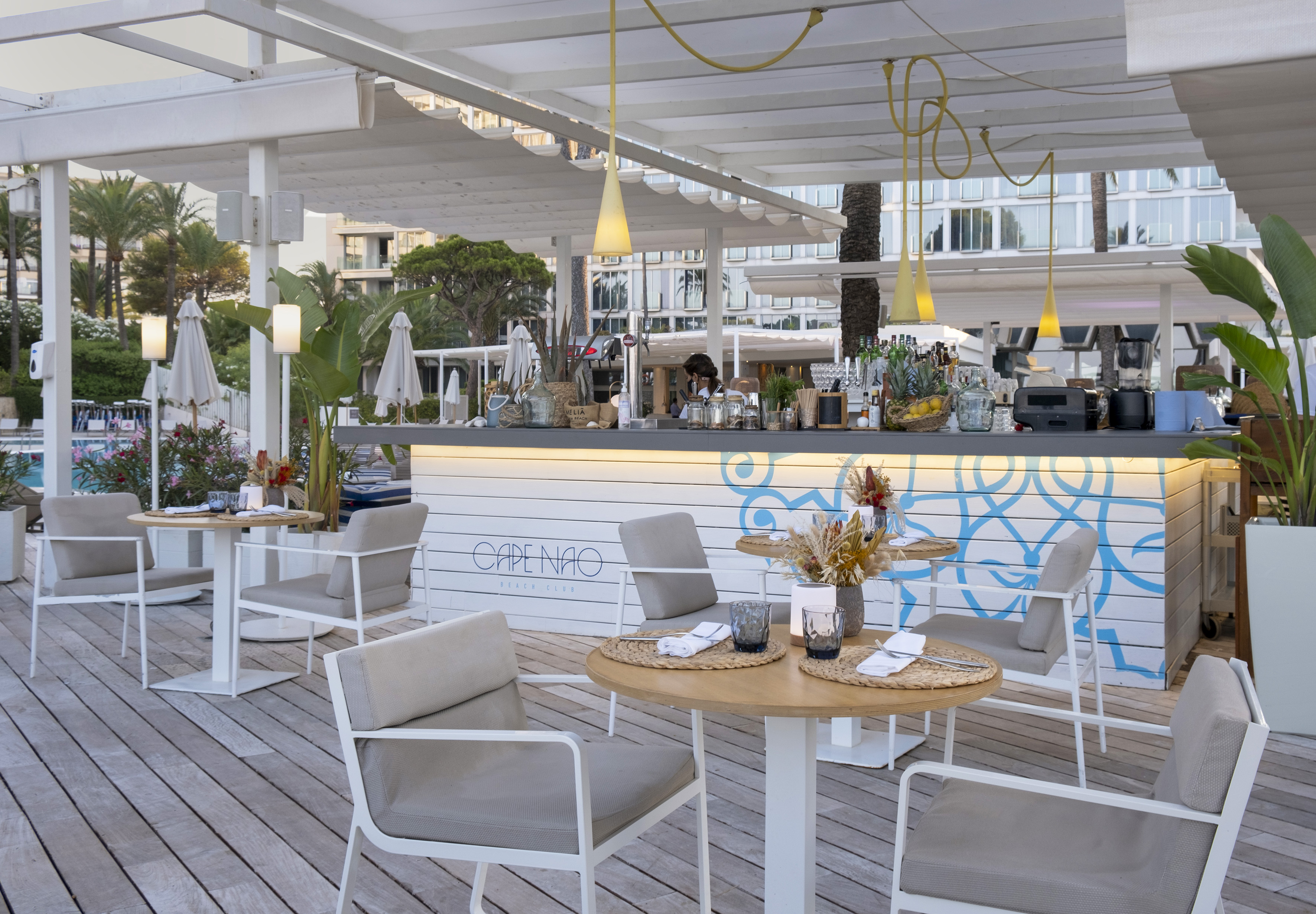 Cape Nao Beach Club outdoor bar with modern furniture on a wooden deck.