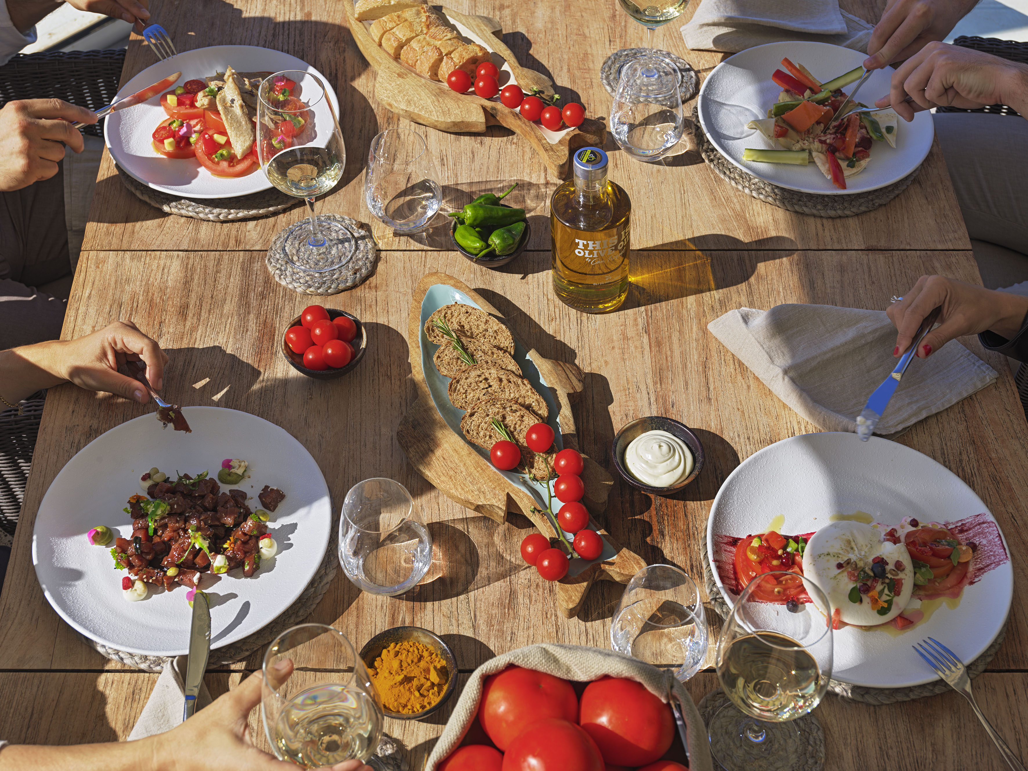 Outdoor Mediterranean meal with tapas, fresh vegetables, olive oil, and wine.
