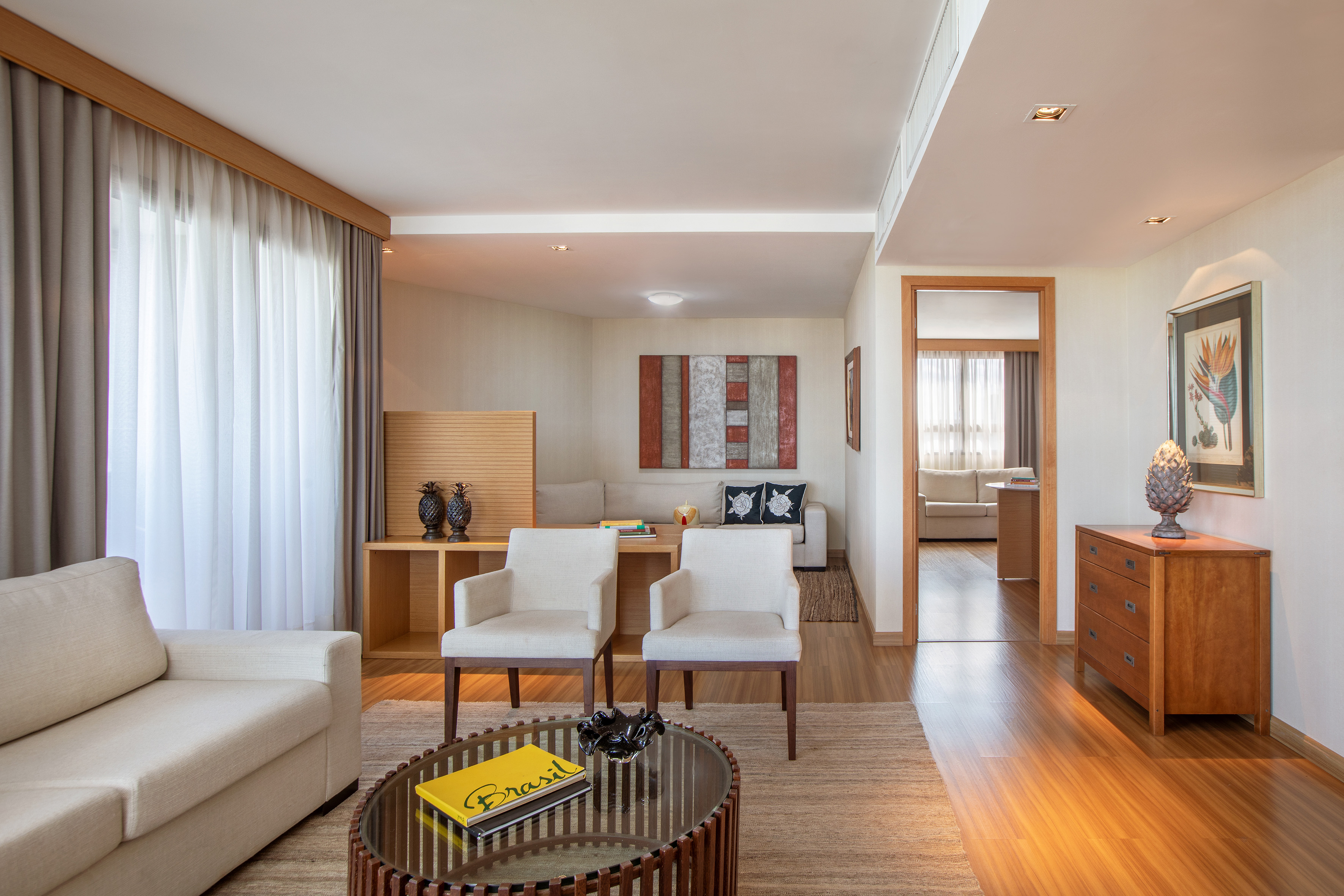 Bright modern living room with neutral furniture, wooden floor, and abstract art.