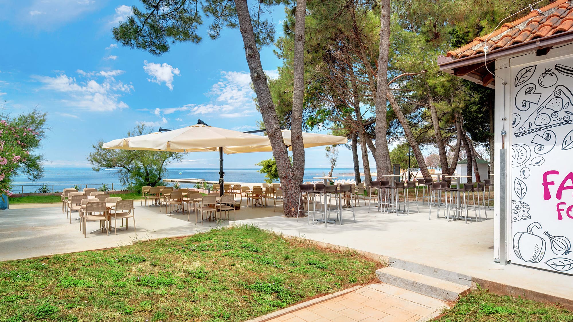 a patio with tables and umbrellas by the water