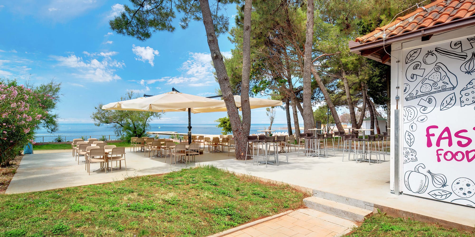 a patio with tables and umbrellas by the water