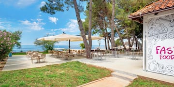 a patio with tables and umbrellas by the water