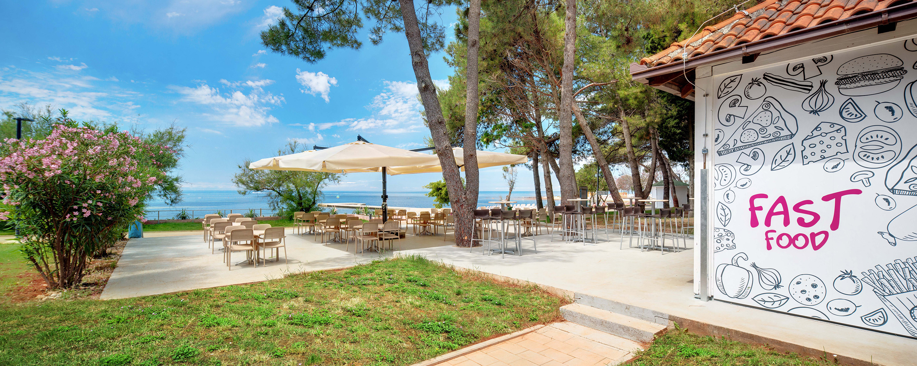 a patio with tables and umbrellas by the water