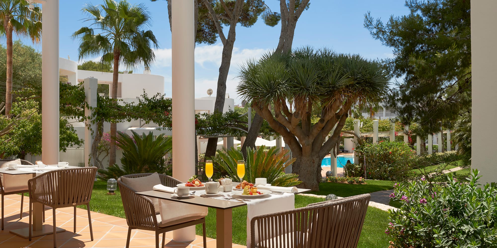 a table and chairs outside with a pool in the background