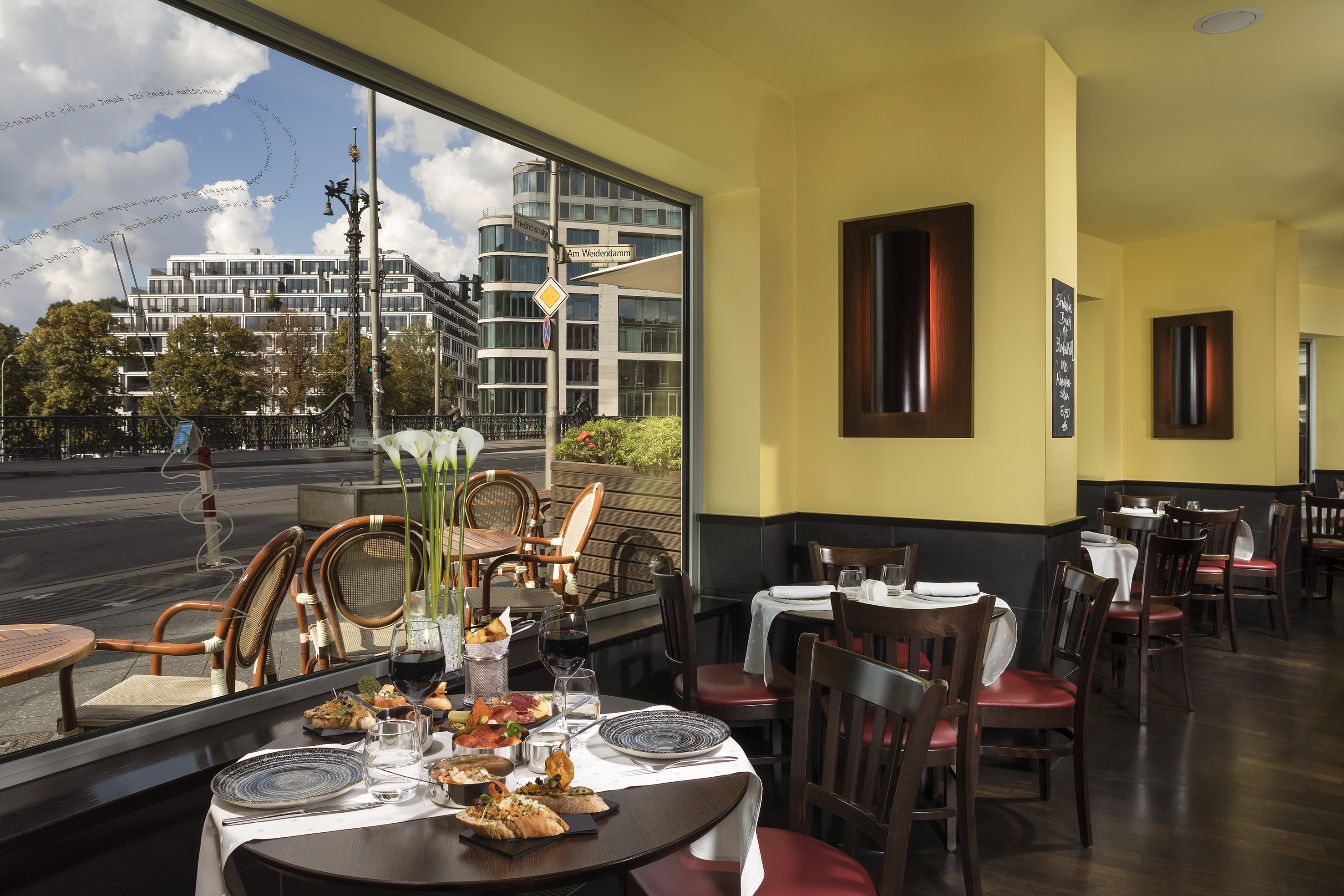 Restaurant dining table with food, wine. Window view of Berlin's Friedrichstraße.