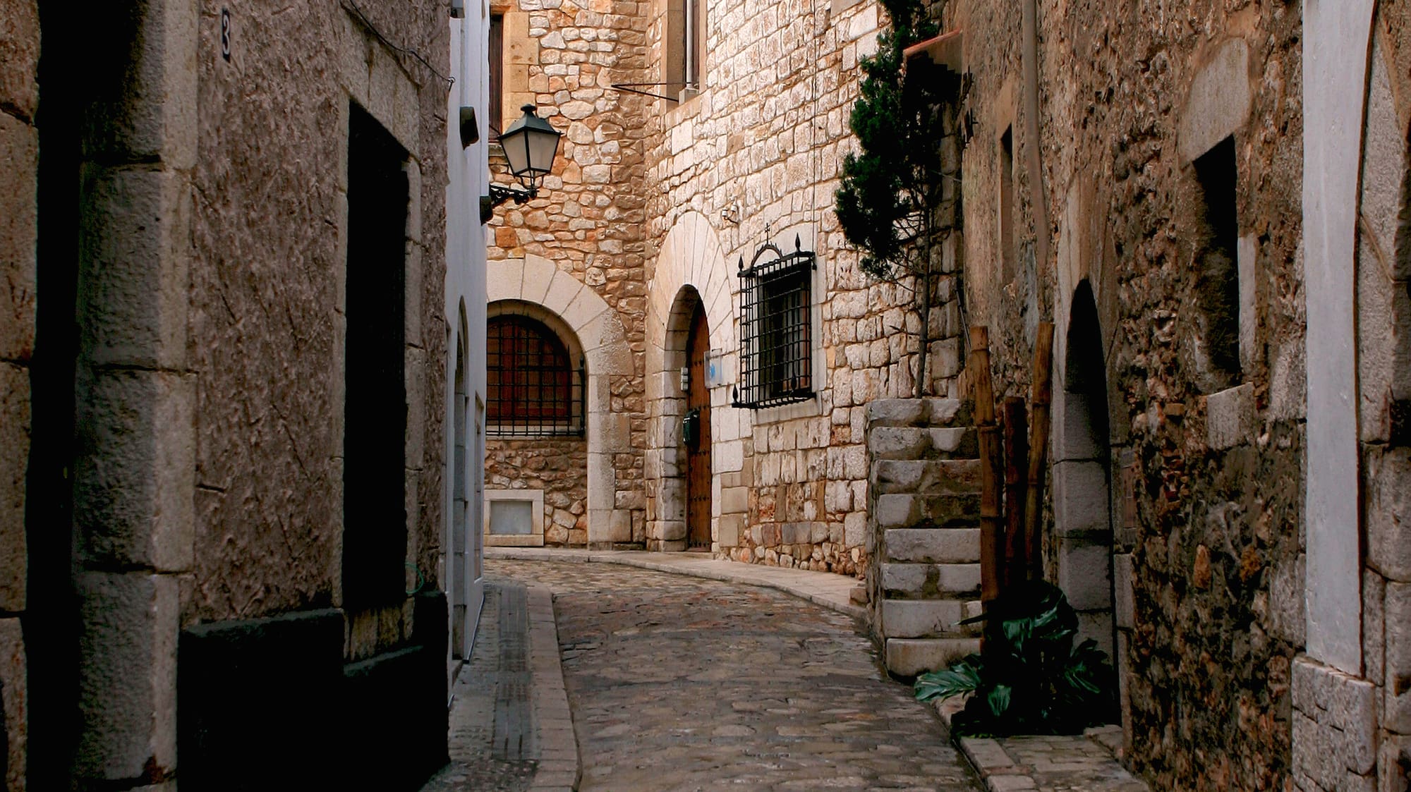 a stone alleyway with stone buildings and a lamp post