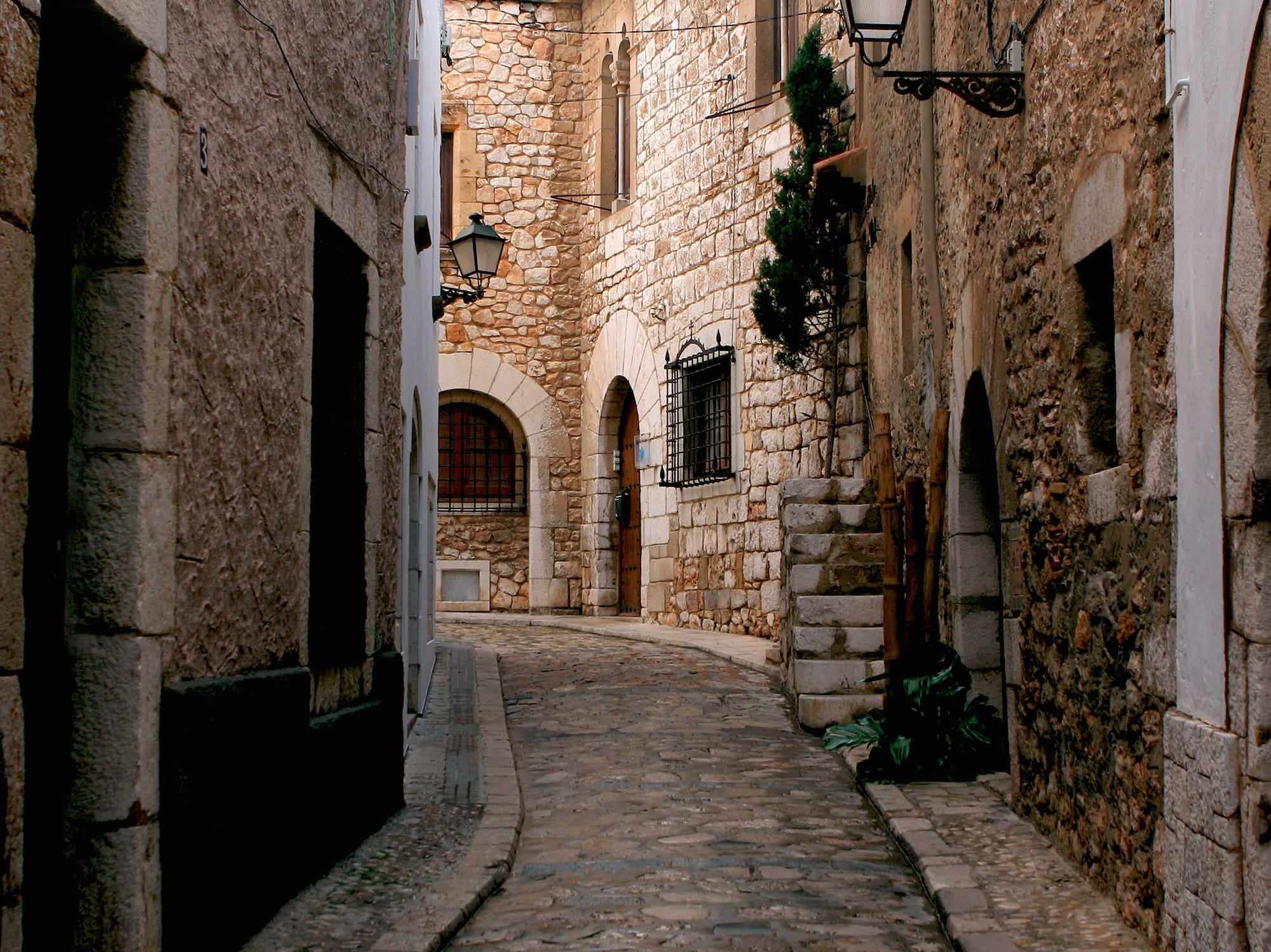 a stone alleyway with stone buildings and a lamp post