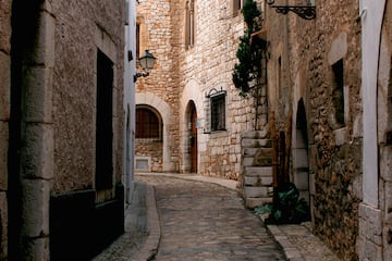 a stone alleyway with stone buildings and a lamp post