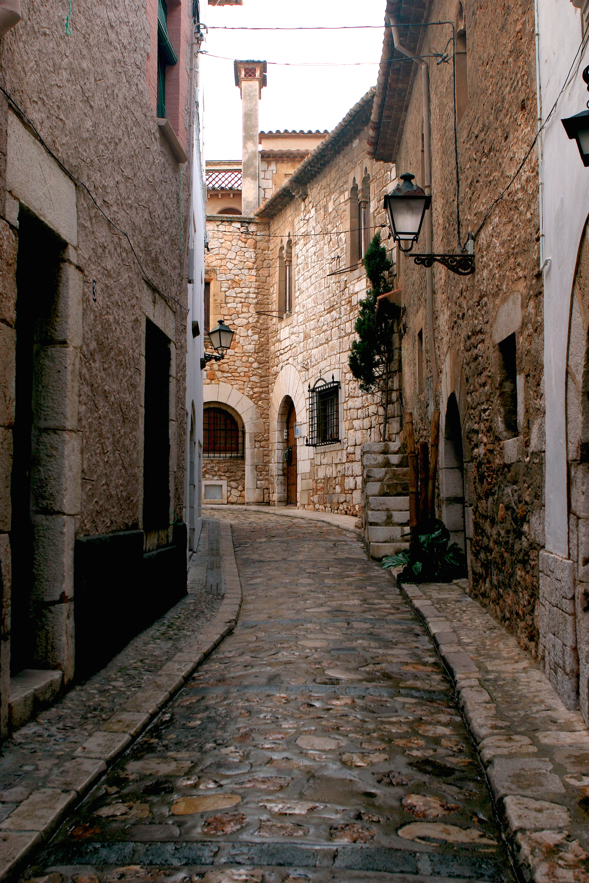 a stone alleyway with stone buildings and a lamp post