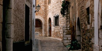 a stone alleyway with stone buildings and a lamp post