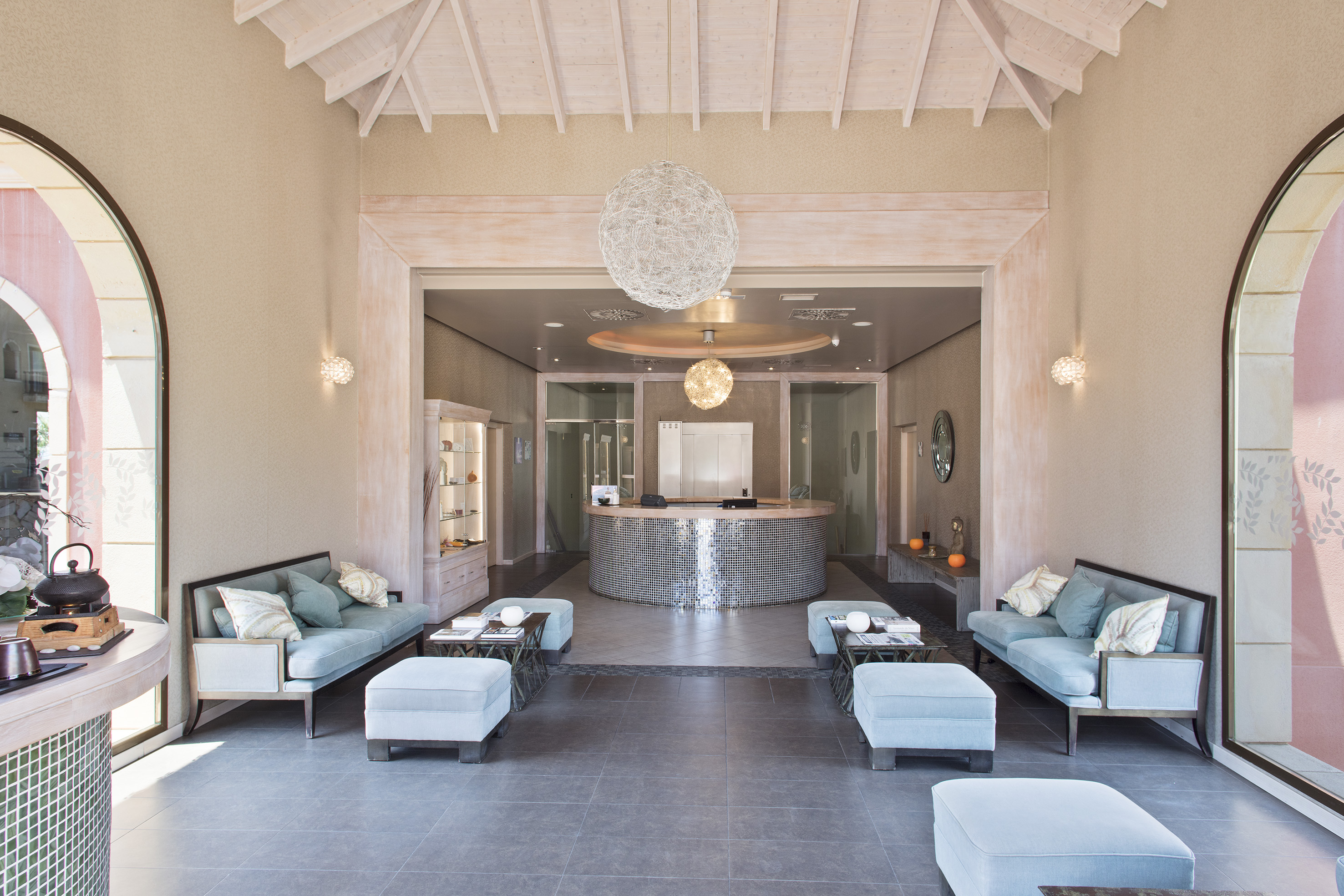 Elegant spa or hotel lobby with light blue sofas and round reception desk.