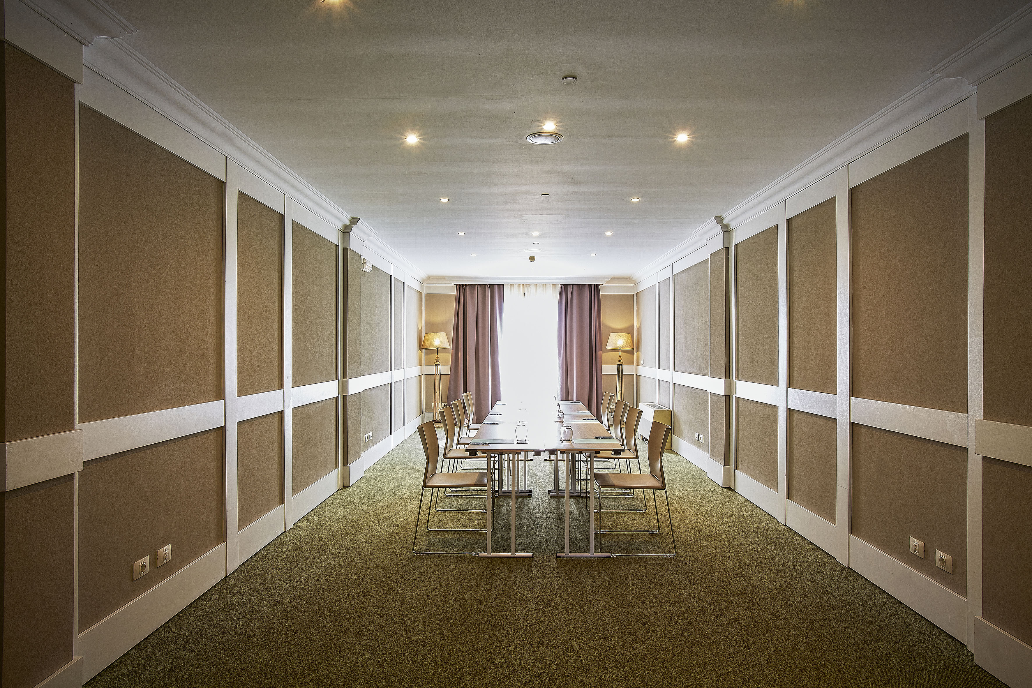 Contemporary meeting room with long conference table, chairs, and paneled walls.